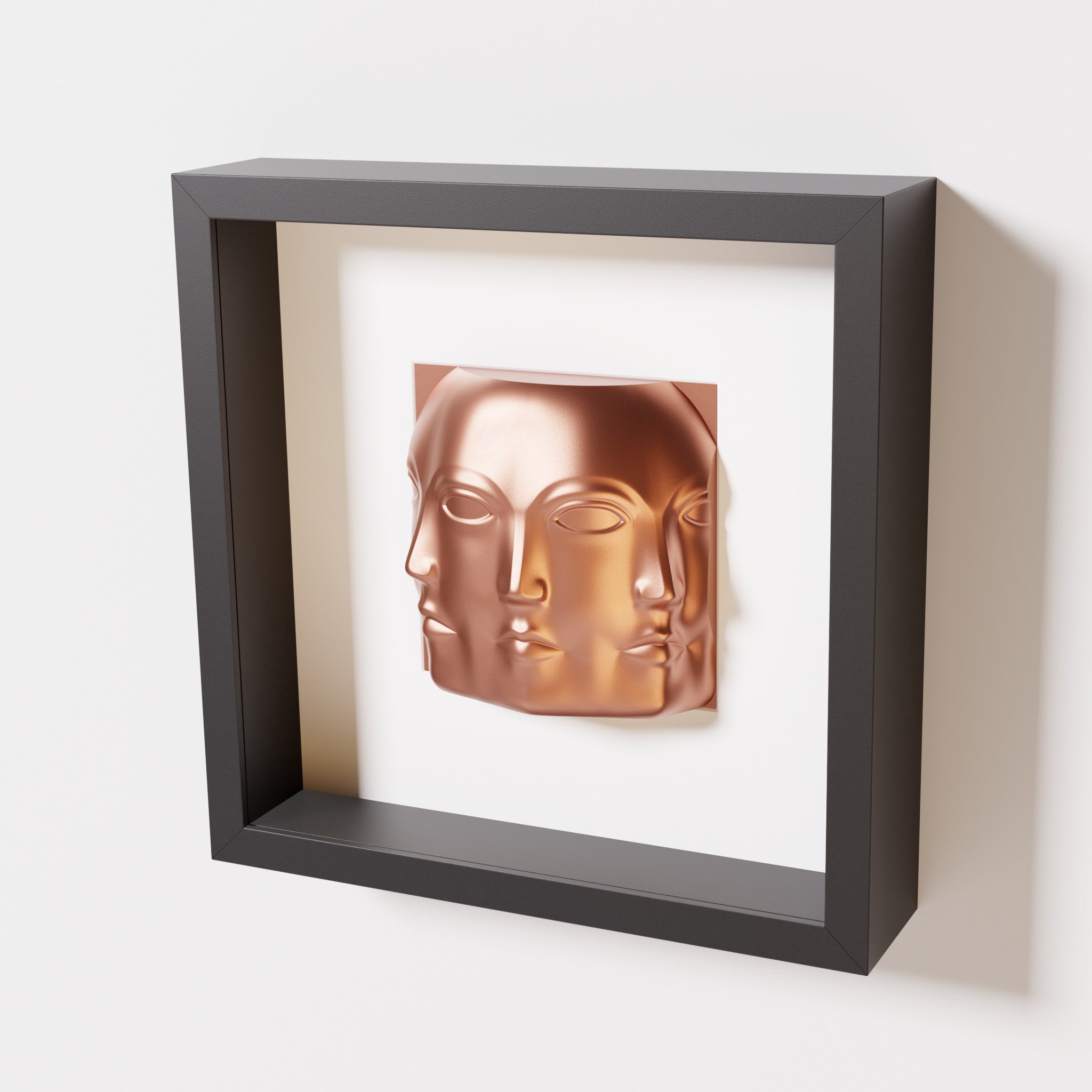 A close-up of a black shadowbox frame containing a chrome copper sculpture of 'Dora,' featuring three interconnected faces merging at the edges, creating a surreal and multi-dimensional effect.