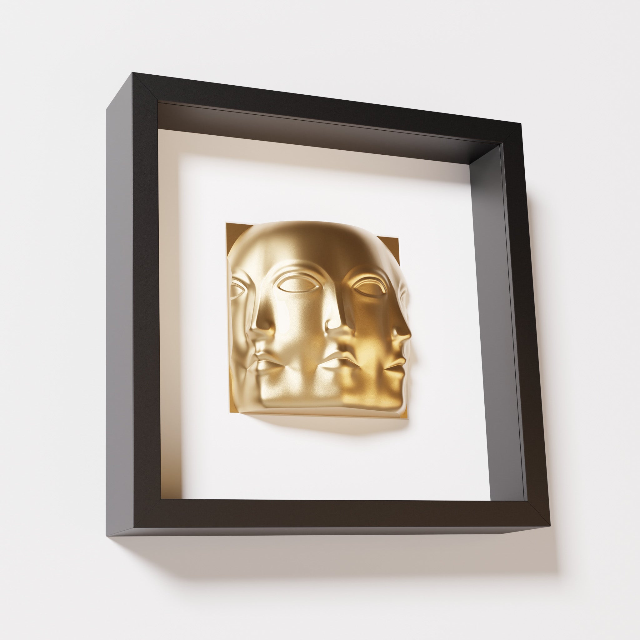 A close-up of a black shadowbox frame containing a chrome gold sculpture of 'Dora,' featuring three interconnected faces merging at the edges, creating a surreal and multi-dimensional effect.