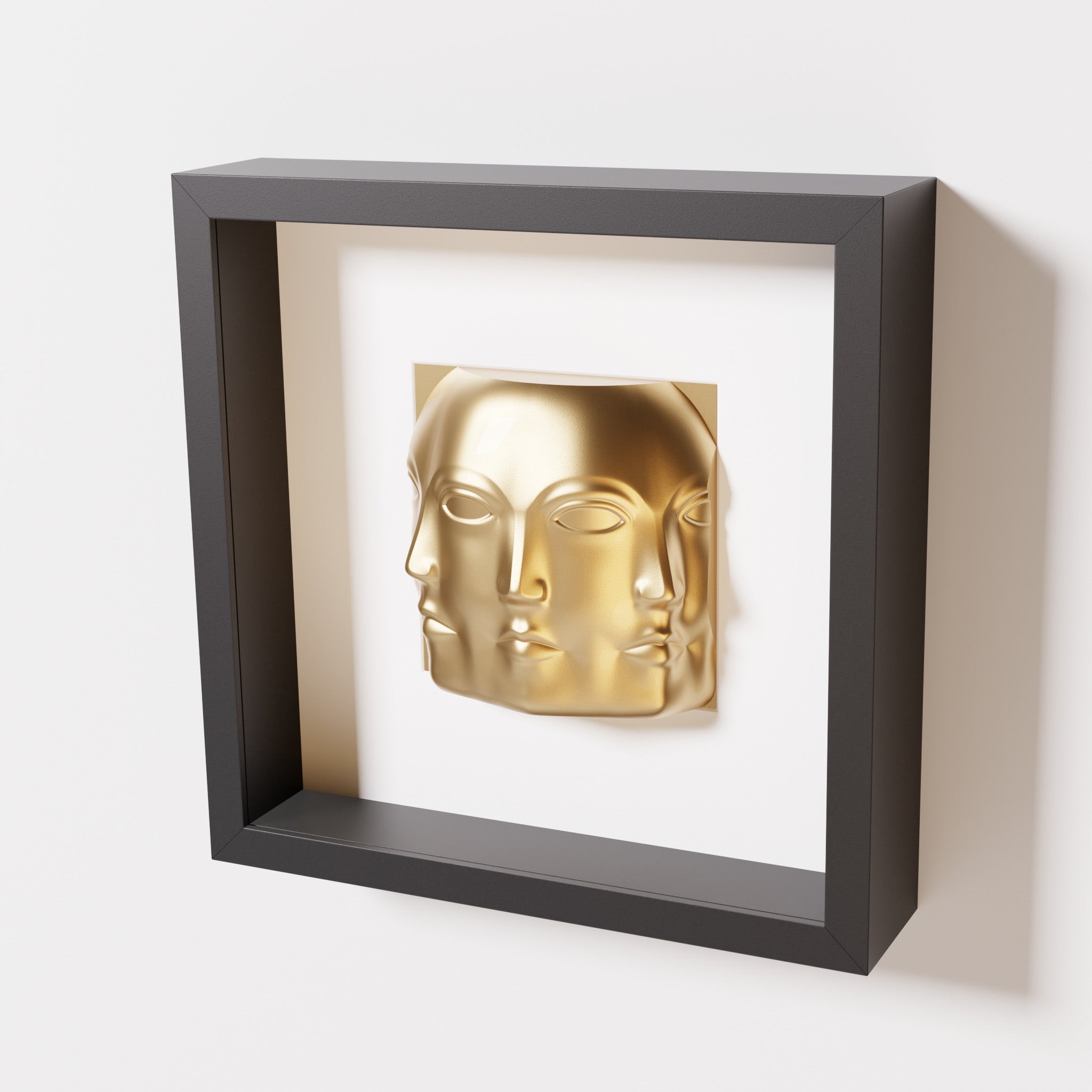 A close-up of a black shadowbox frame containing a chrome gold sculpture of 'Dora,' featuring three interconnected faces merging at the edges, creating a surreal and multi-dimensional effect.