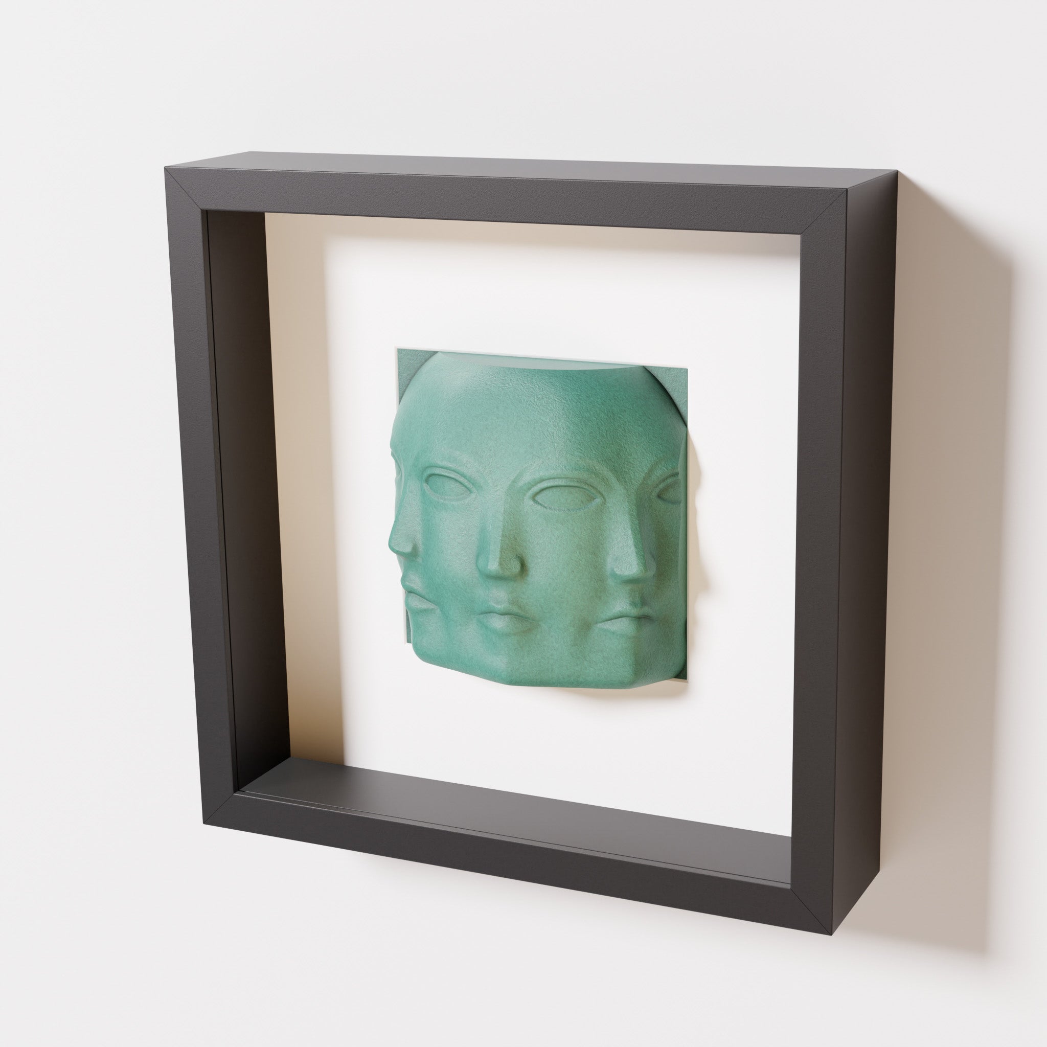 A close-up of a black shadowbox frame containing an old patina sculpture of 'Dora,' featuring three interconnected faces merging at the edges, creating a surreal and multi-dimensional effect.