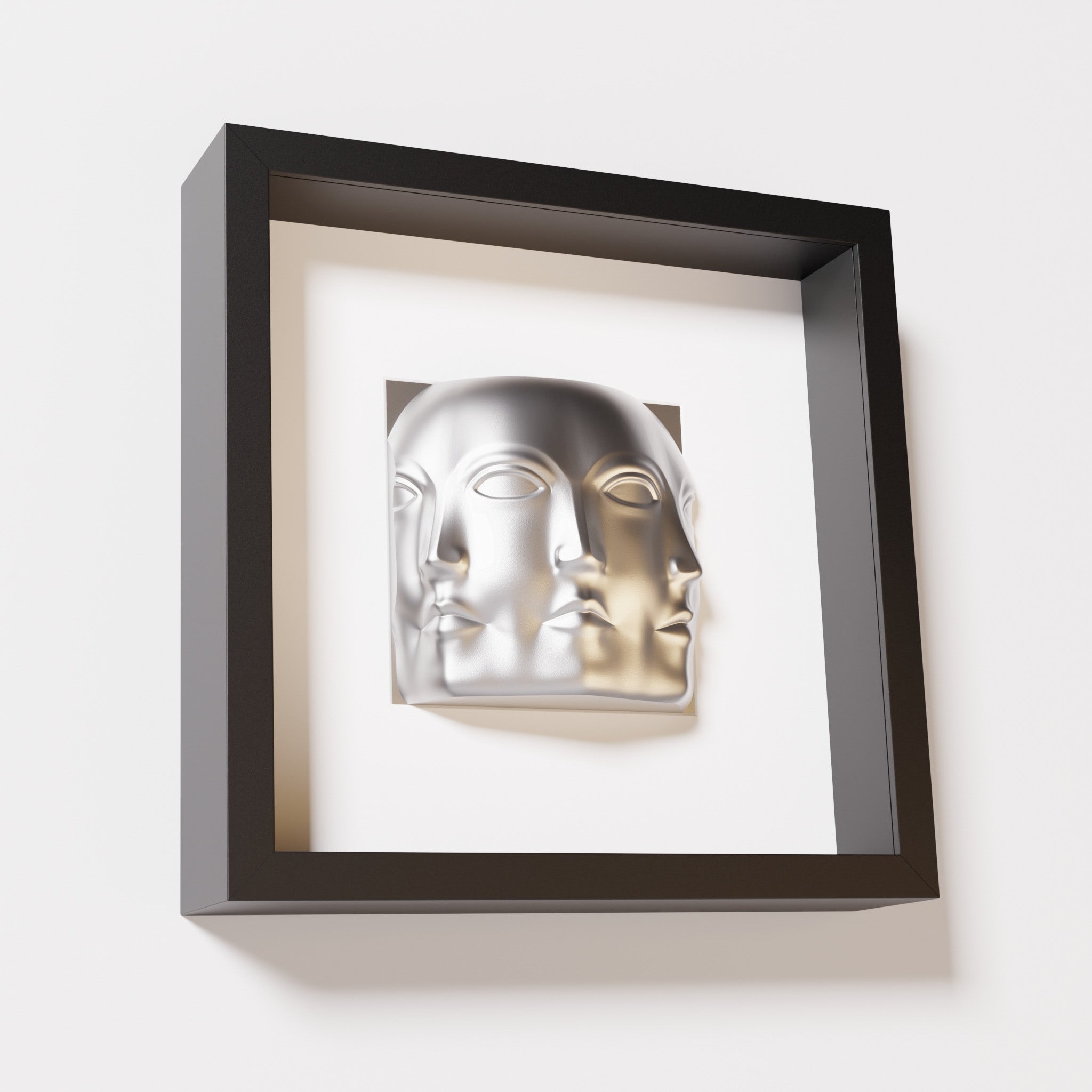 A close-up of a black shadowbox frame containing a chrome silver sculpture of 'Dora,' featuring three interconnected faces merging at the edges, creating a surreal and multi-dimensional effect.