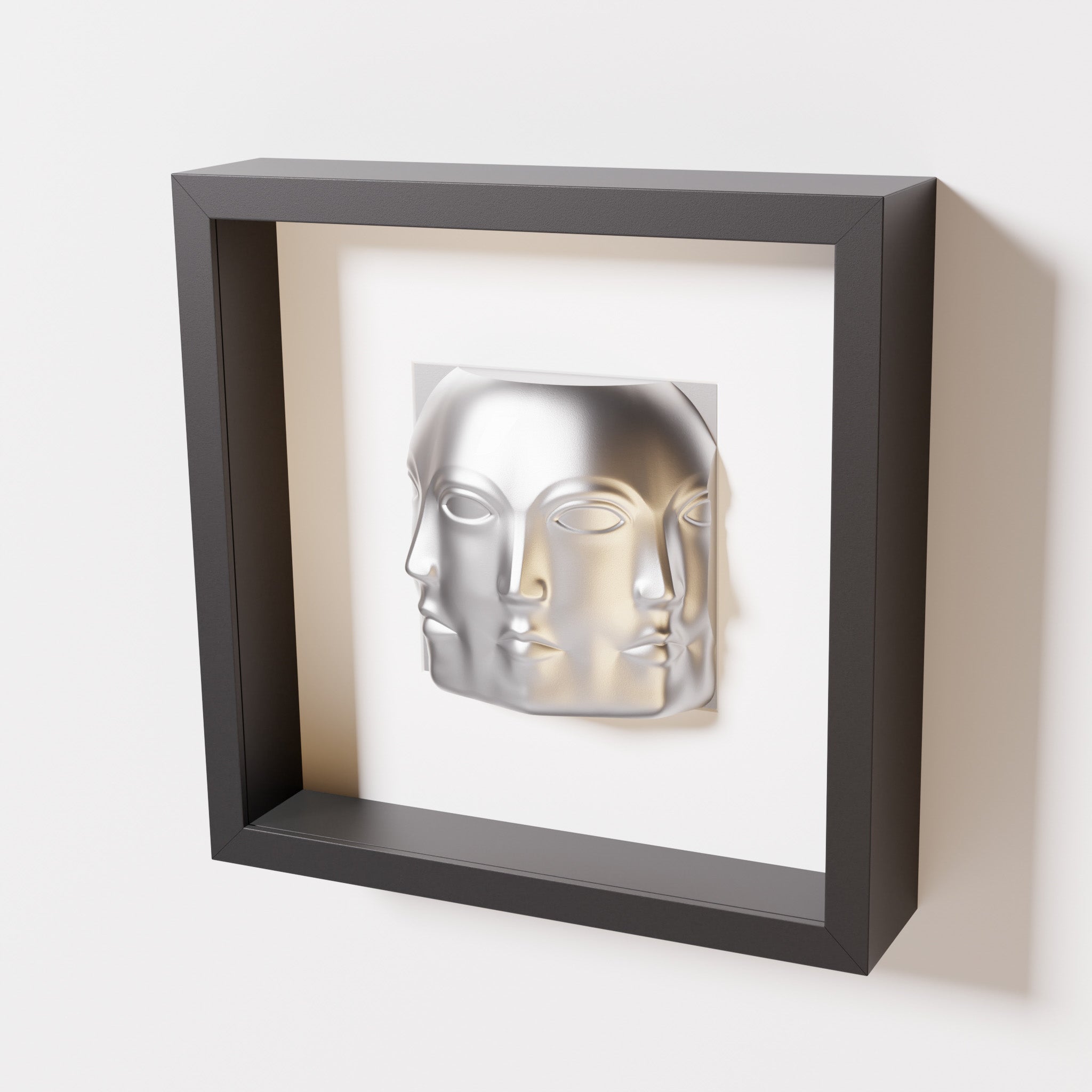 A close-up of a black shadowbox frame containing a chrome silver sculpture of 'Dora,' featuring three interconnected faces merging at the edges, creating a surreal and multi-dimensional effect.