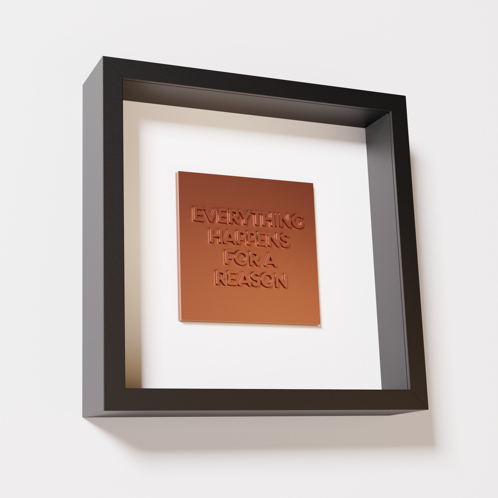 A close-up of a black shadowbox frame containing a chrome copper artwork featuring the thoughtful phrase 'Everything Happens for a Reason,' emphasizing its reflective copper highlights.