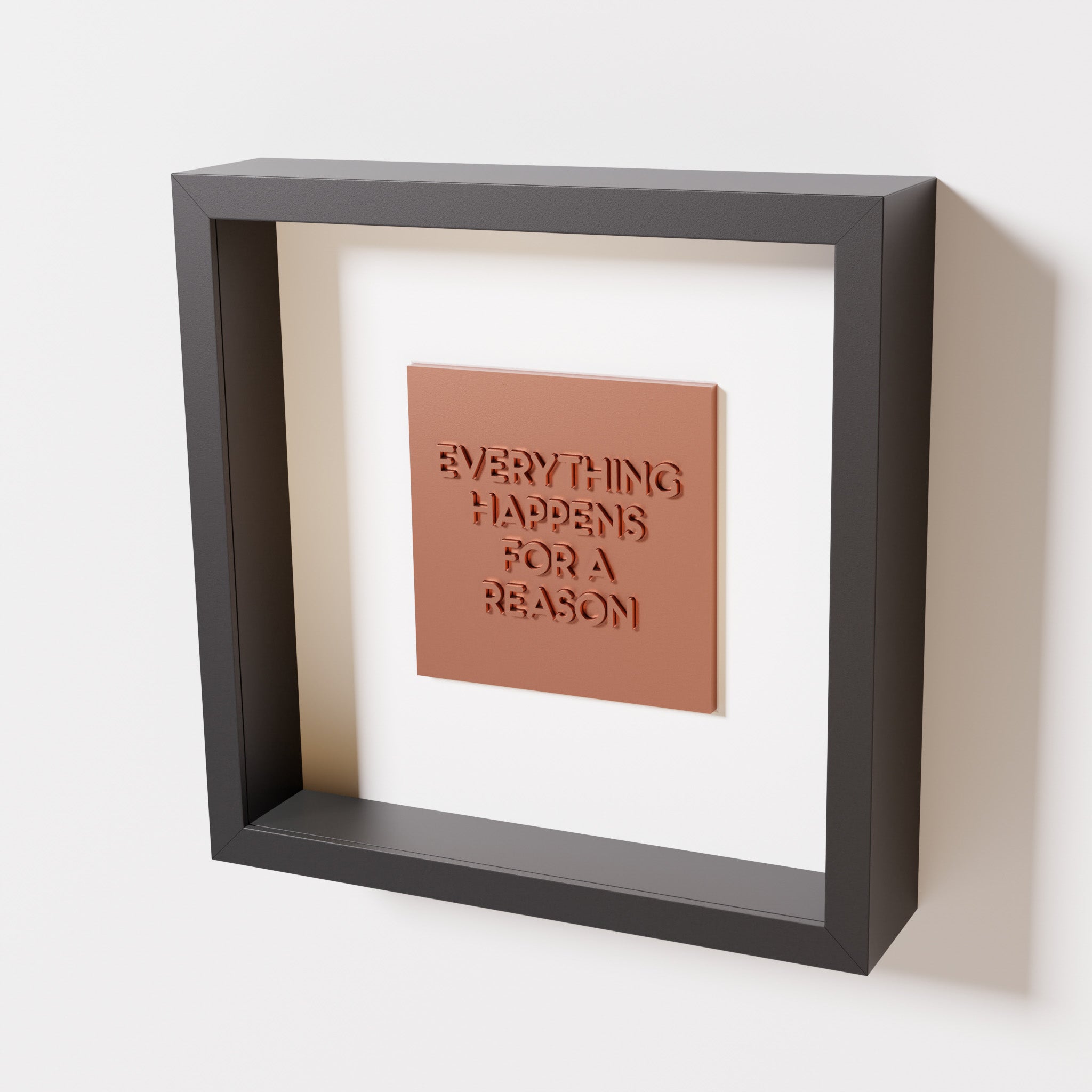 A close-up of a black shadowbox frame containing a chrome copper artwork featuring the thoughtful phrase 'Everything Happens for a Reason,' emphasizing its reflective copper highlights.