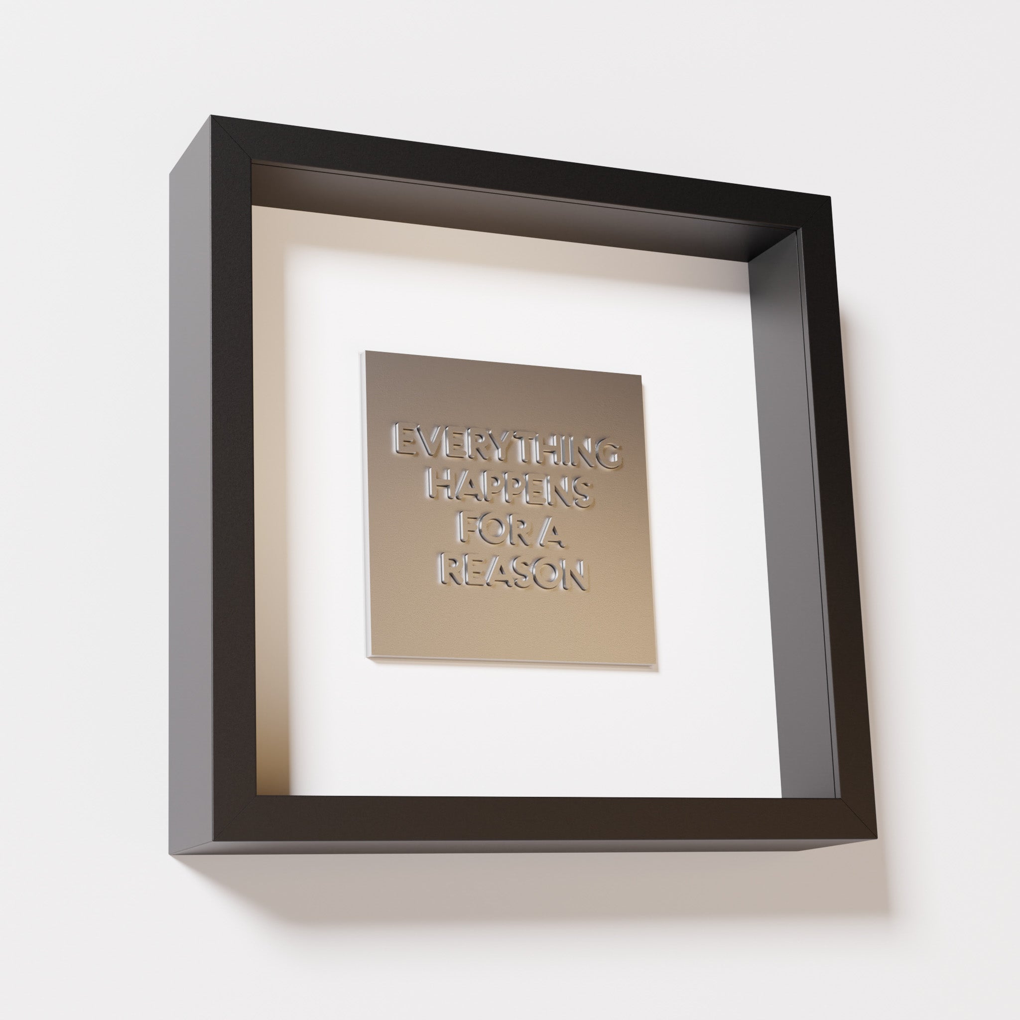 A close-up of a black shadowbox frame containing a chrome silver artwork featuring the thoughtful phrase 'Everything Happens for a Reason,' emphasizing its reflective silver highlights.