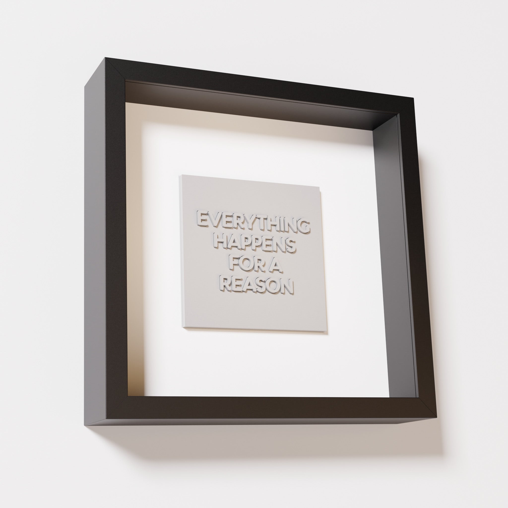 A close-up of a black shadowbox frame containing a marble white artwork featuring the thoughtful phrase 'Everything Happens for a Reason,' emphasizing its intricate text and modern design.