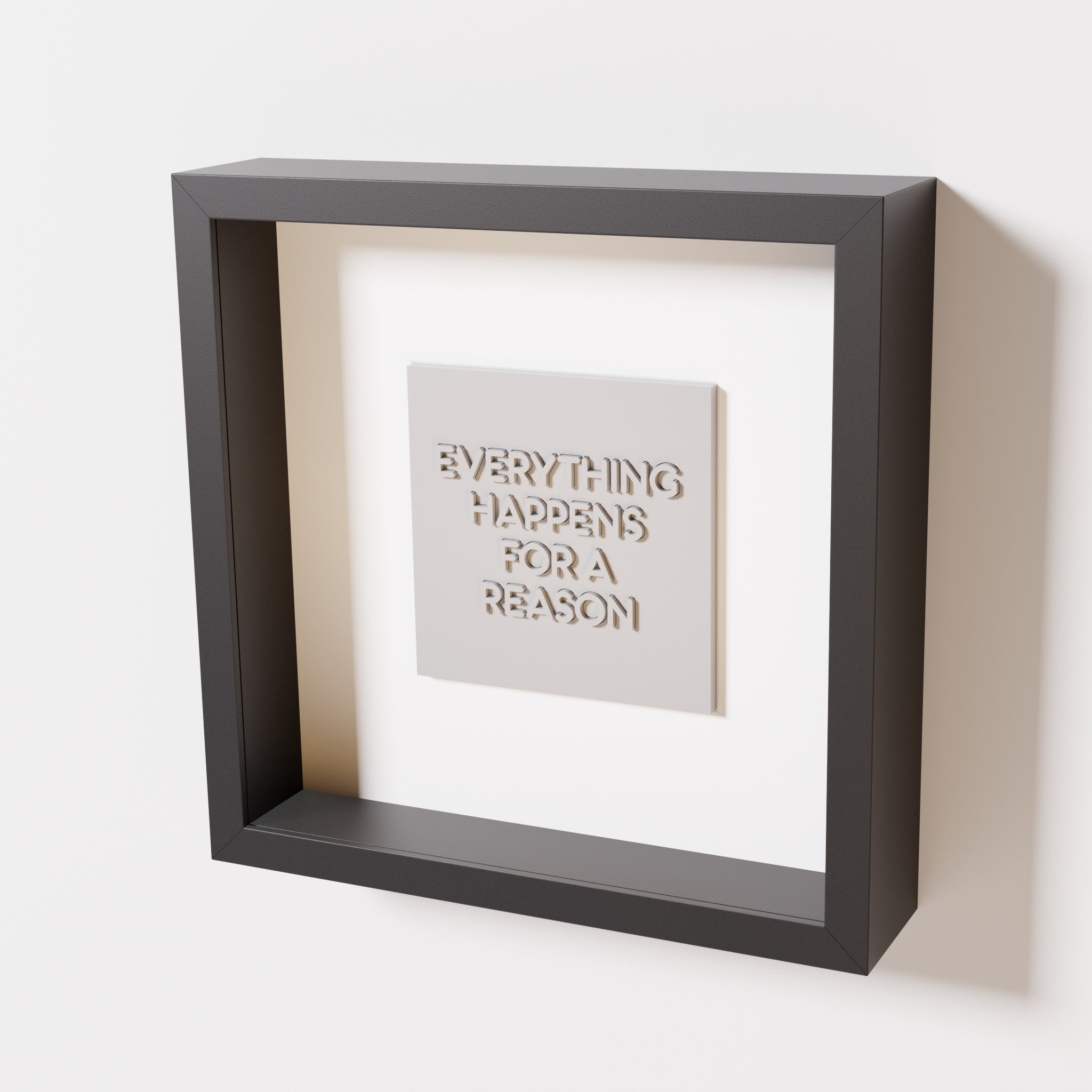 A close-up of a black shadowbox frame containing a marble white artwork featuring the thoughtful phrase 'Everything Happens for a Reason,' emphasizing its intricate text and modern design.