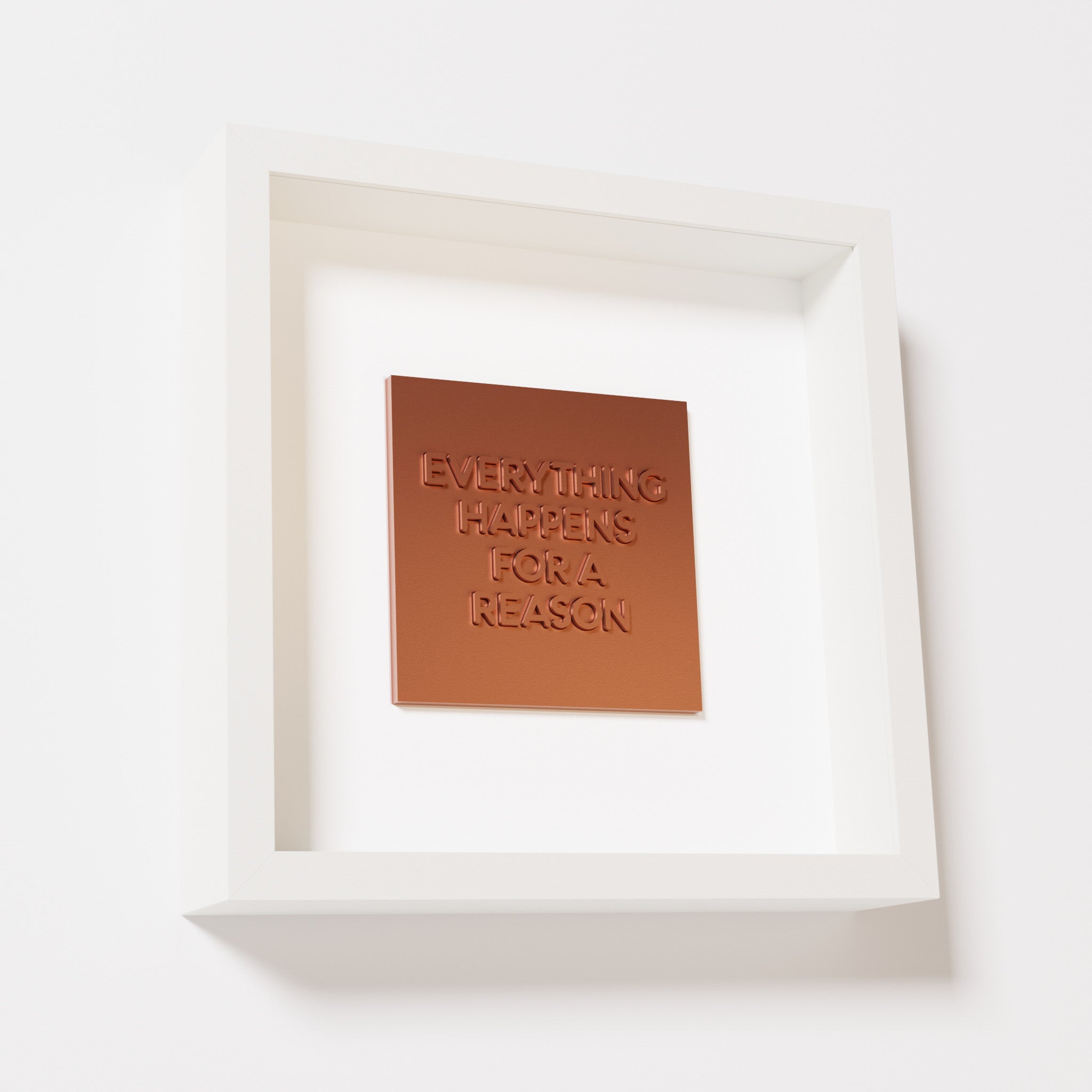 A close-up of a white shadowbox frame containing a chrome copper artwork featuring the thoughtful phrase 'Everything Happens for a Reason,' emphasizing its reflective copper highlights.