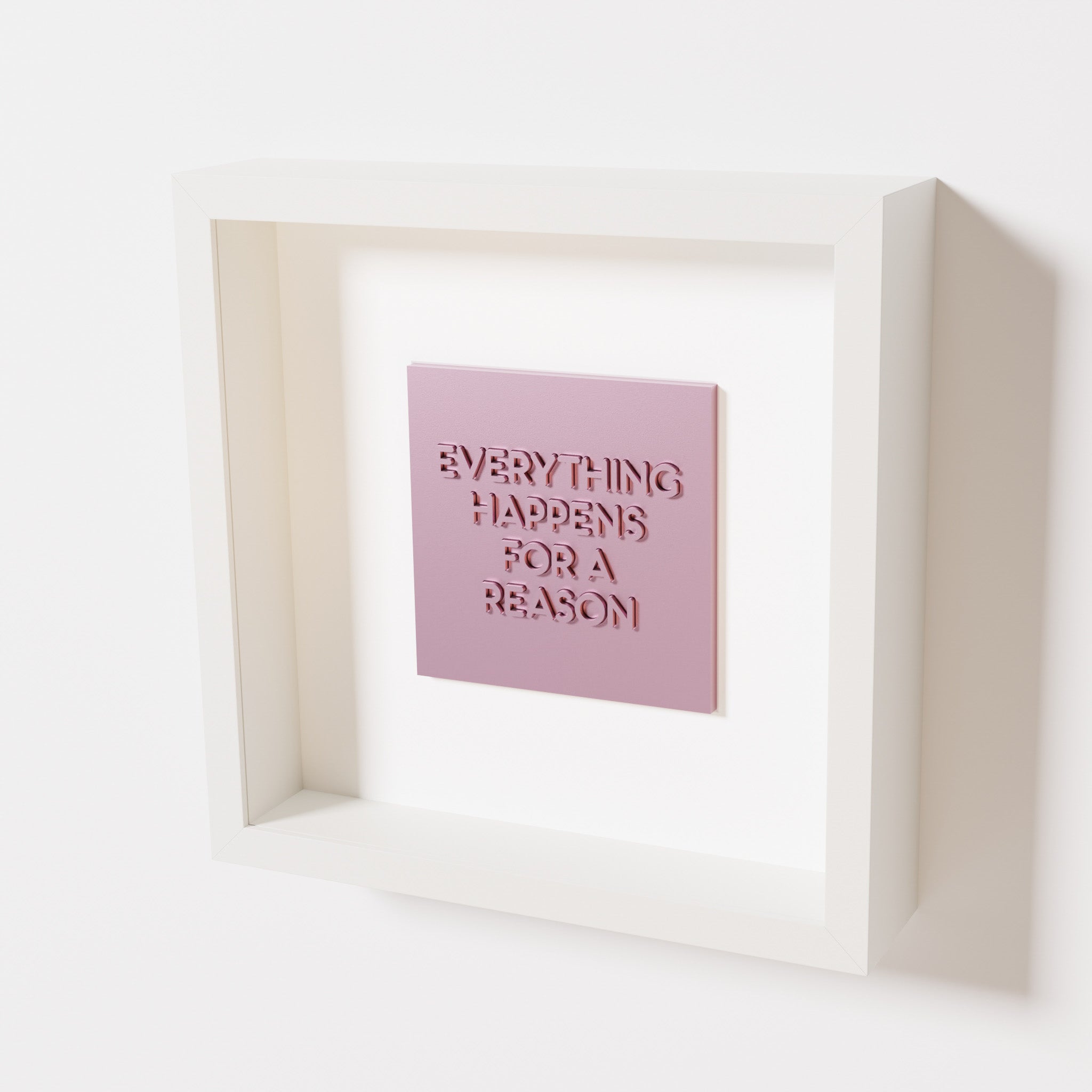 A close-up of a white shadowbox frame containing a metallic rose artwork featuring the thoughtful phrase 'Everything Happens for a Reason,' showcasing reflective pink highlights.