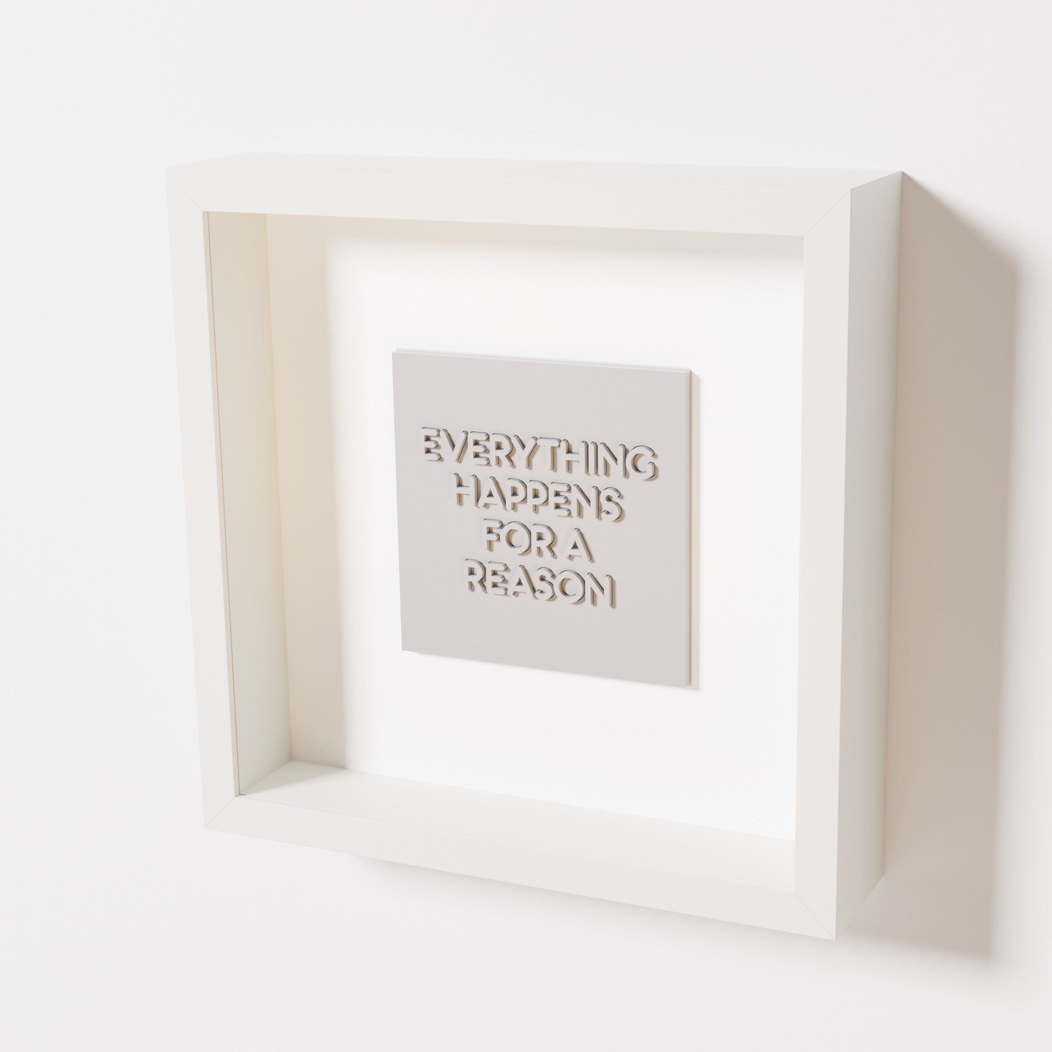 A close-up of a white shadowbox frame containing a marble white artwork featuring the thoughtful phrase 'Everything Happens for a Reason,' emphasizing its intricate text and modern design.