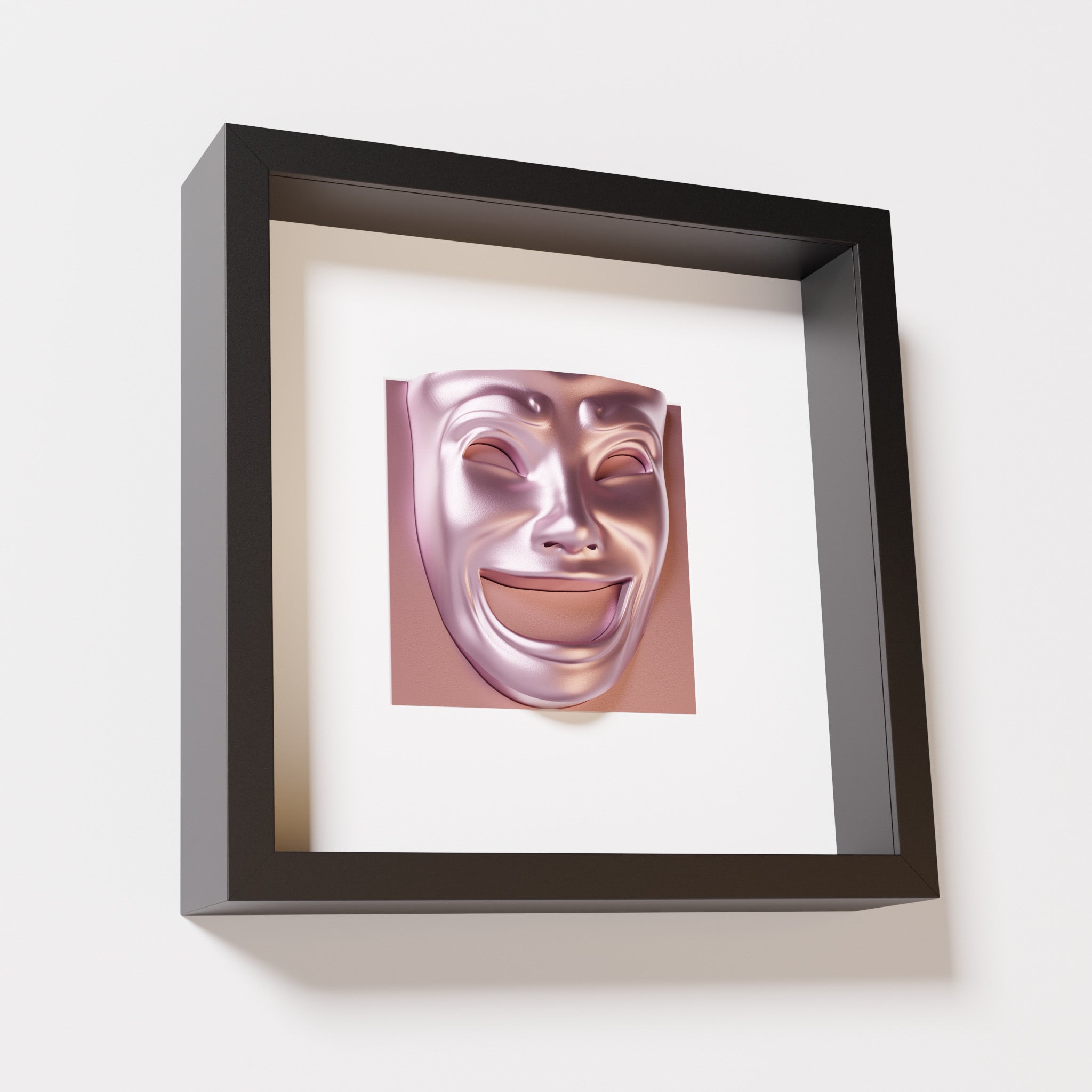 A close-up of a black shadowbox frame containing a metallic rose sculpture of 'Joy,' featuring a theatrical mask with a wide smile and expressive features, evoking happiness and positivity.