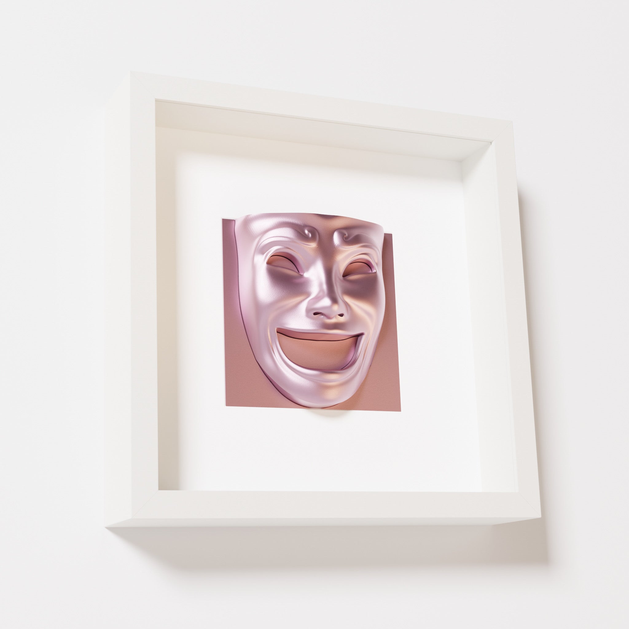 A close-up of a white shadowbox frame containing a metallic rose sculpture of 'Joy,' featuring a theatrical mask with a wide smile and expressive features, evoking happiness and positivity.