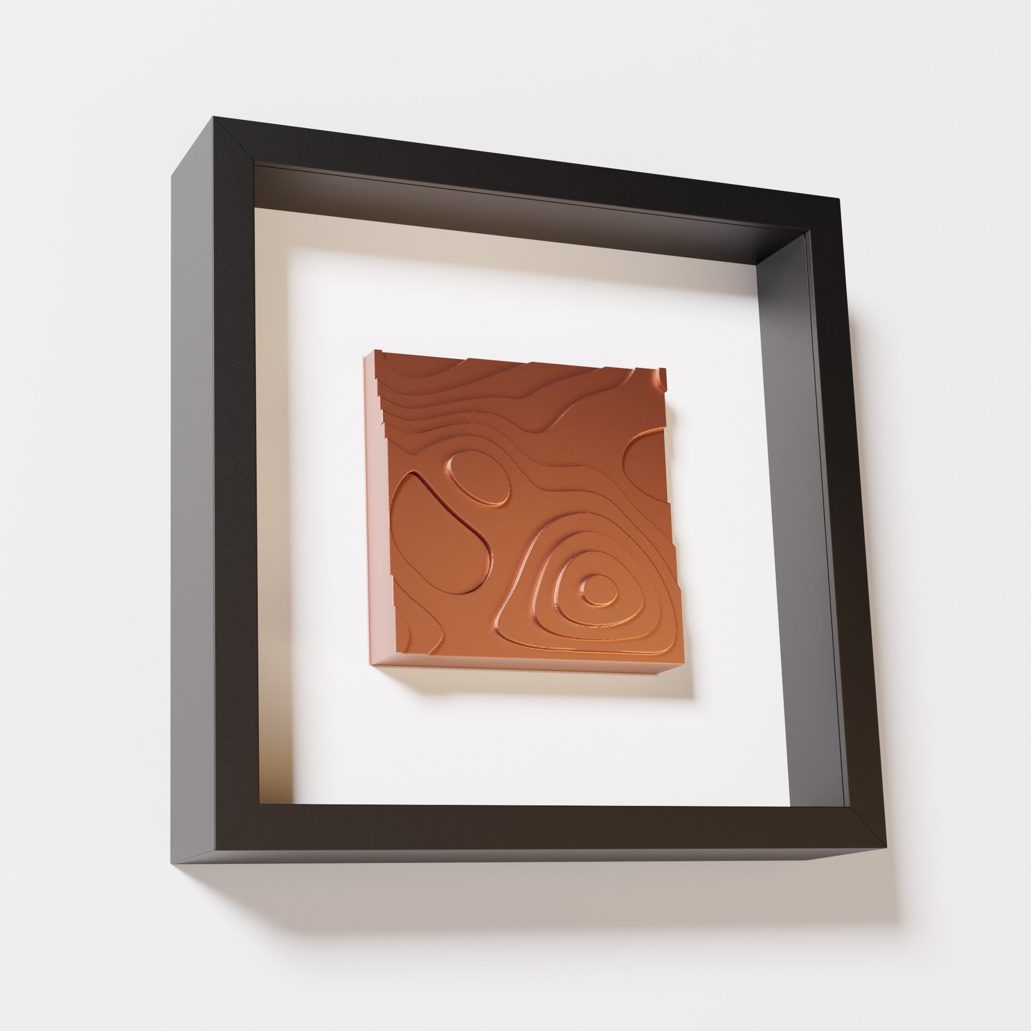 A close-up of a black shadowbox frame containing a chrome copper artwork depicting layered contour lines inspired by geographic elevation levels, showcasing reflective copper details.