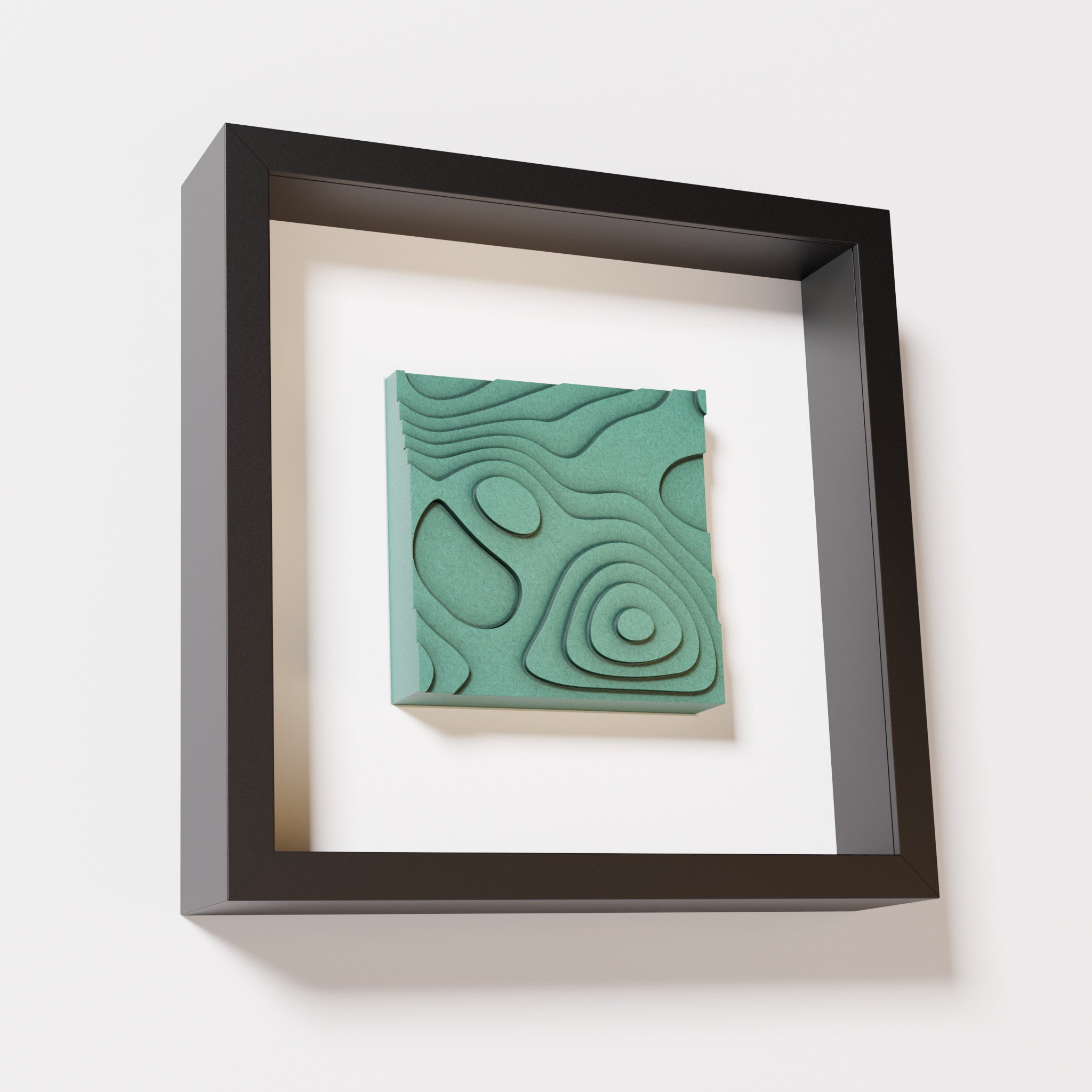 A close-up of a black shadowbox frame containing an old patina artwork depicting layered contour lines inspired by geographic elevation levels, showcasing intricate and geometric details with a textured green finish.