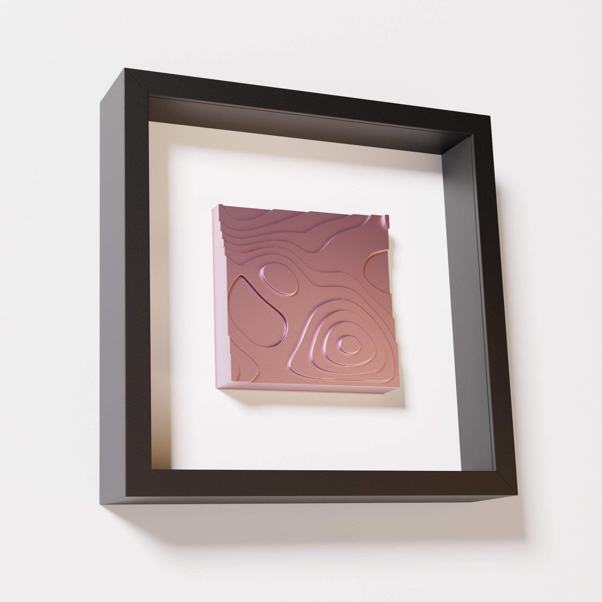 A close-up of a black shadowbox frame containing a metallic rose artwork depicting layered contour lines inspired by geographic elevation levels, showcasing reflective pink details.