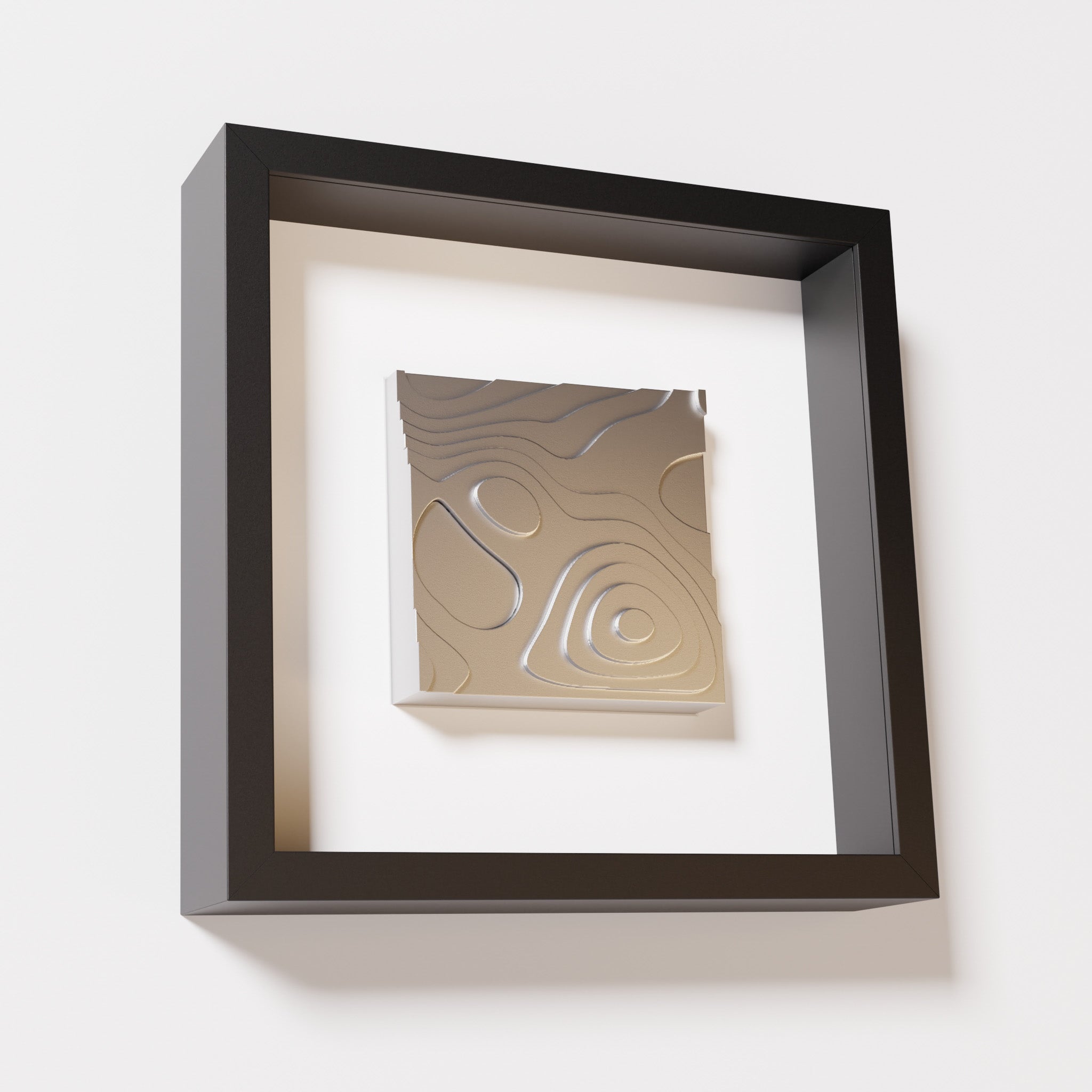 A close-up of a black shadowbox frame containing a chrome silver artwork depicting layered contour lines inspired by geographic elevation levels, showcasing reflective silver details.