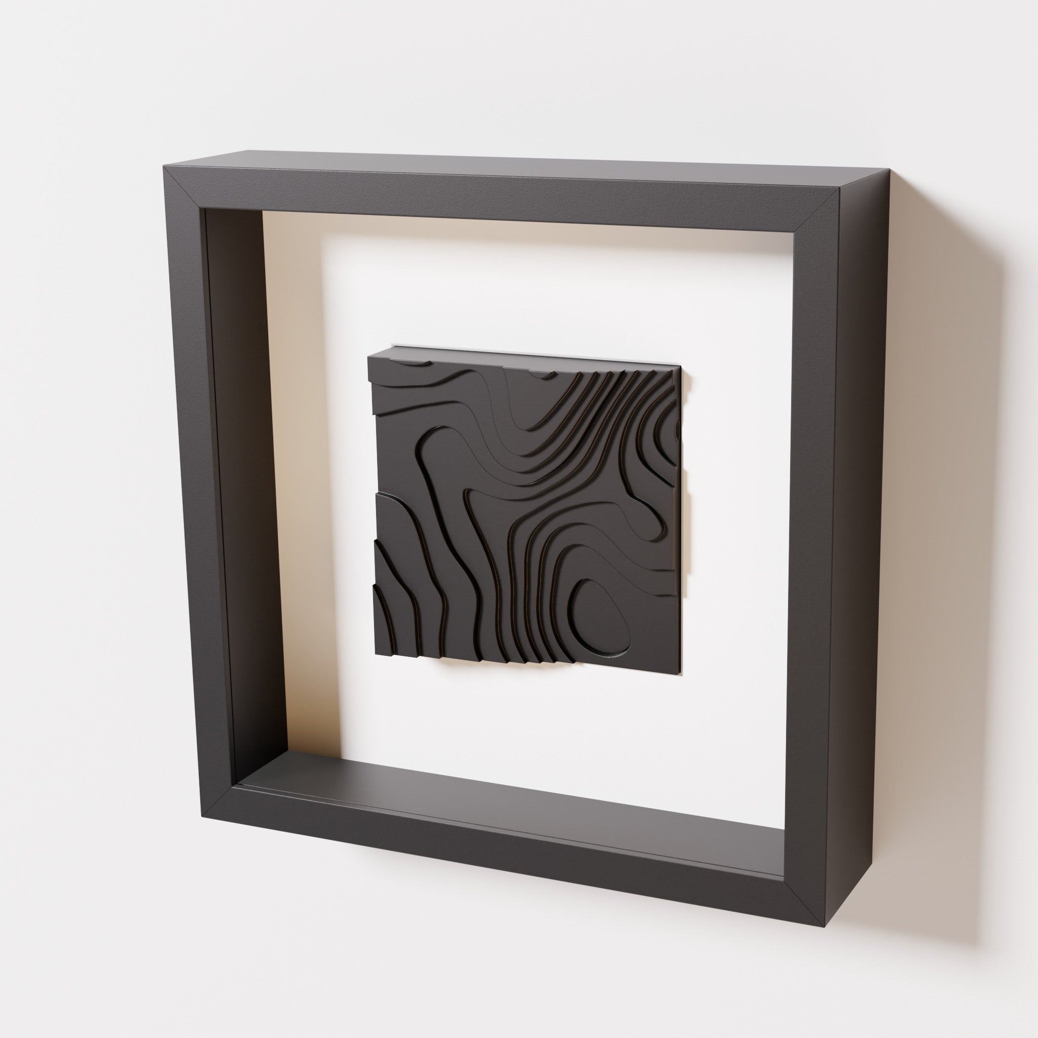 A close-up of a black shadowbox frame containing a matte black artwork depicting flowing contour lines inspired by geographic elevation levels, showcasing intricate geometric details.