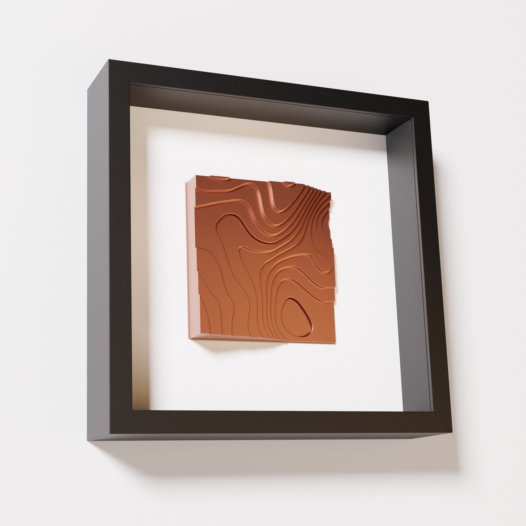 A close-up of a black shadowbox frame containing a chrome copper artwork depicting flowing contour lines inspired by geographic elevation levels, showcasing reflective copper details.