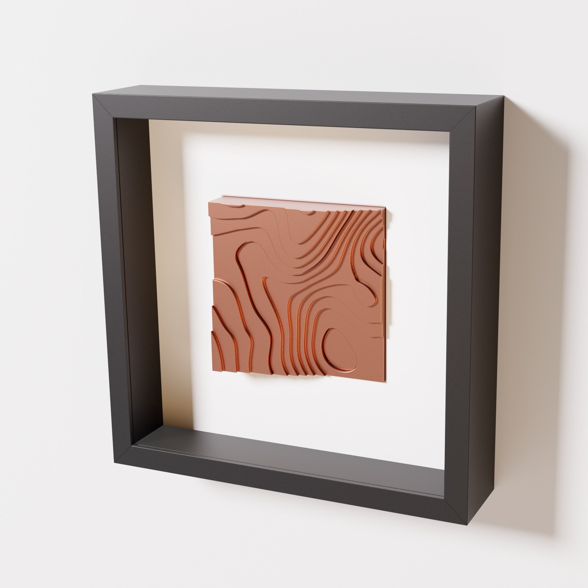 A close-up of a black shadowbox frame containing a chrome copper artwork depicting flowing contour lines inspired by geographic elevation levels, showcasing reflective copper details.