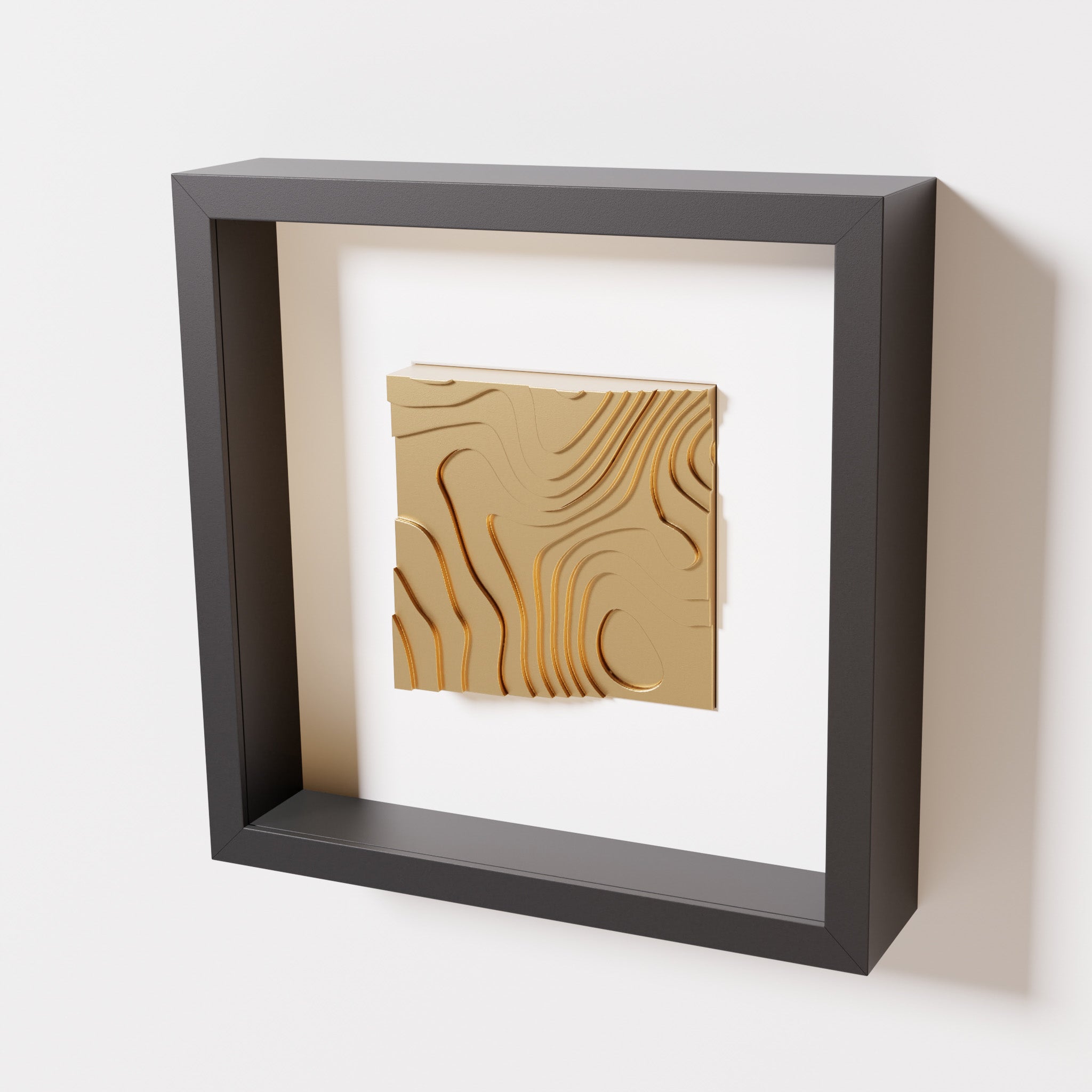 A close-up of a black shadowbox frame containing a chrome gold artwork depicting flowing contour lines inspired by geographic elevation levels, showcasing reflective golden details.