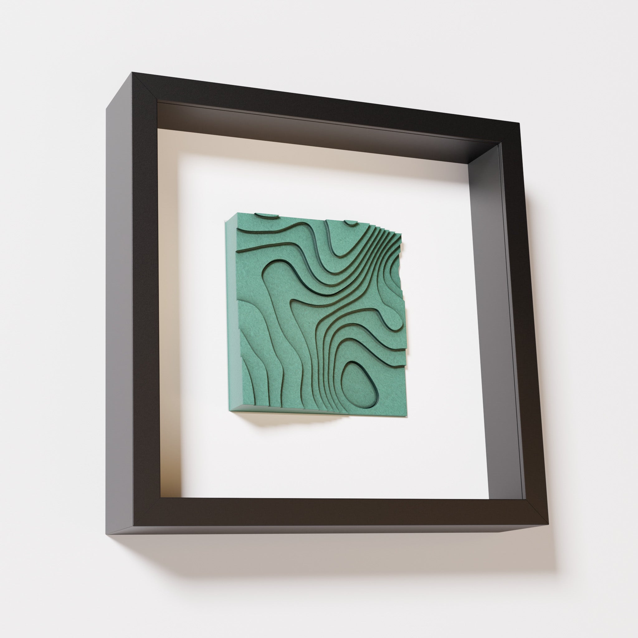 A close-up of a black shadowbox frame containing an old patina artwork depicting flowing contour lines inspired by geographic elevation levels, showcasing intricate geometric details with a textured green finish.