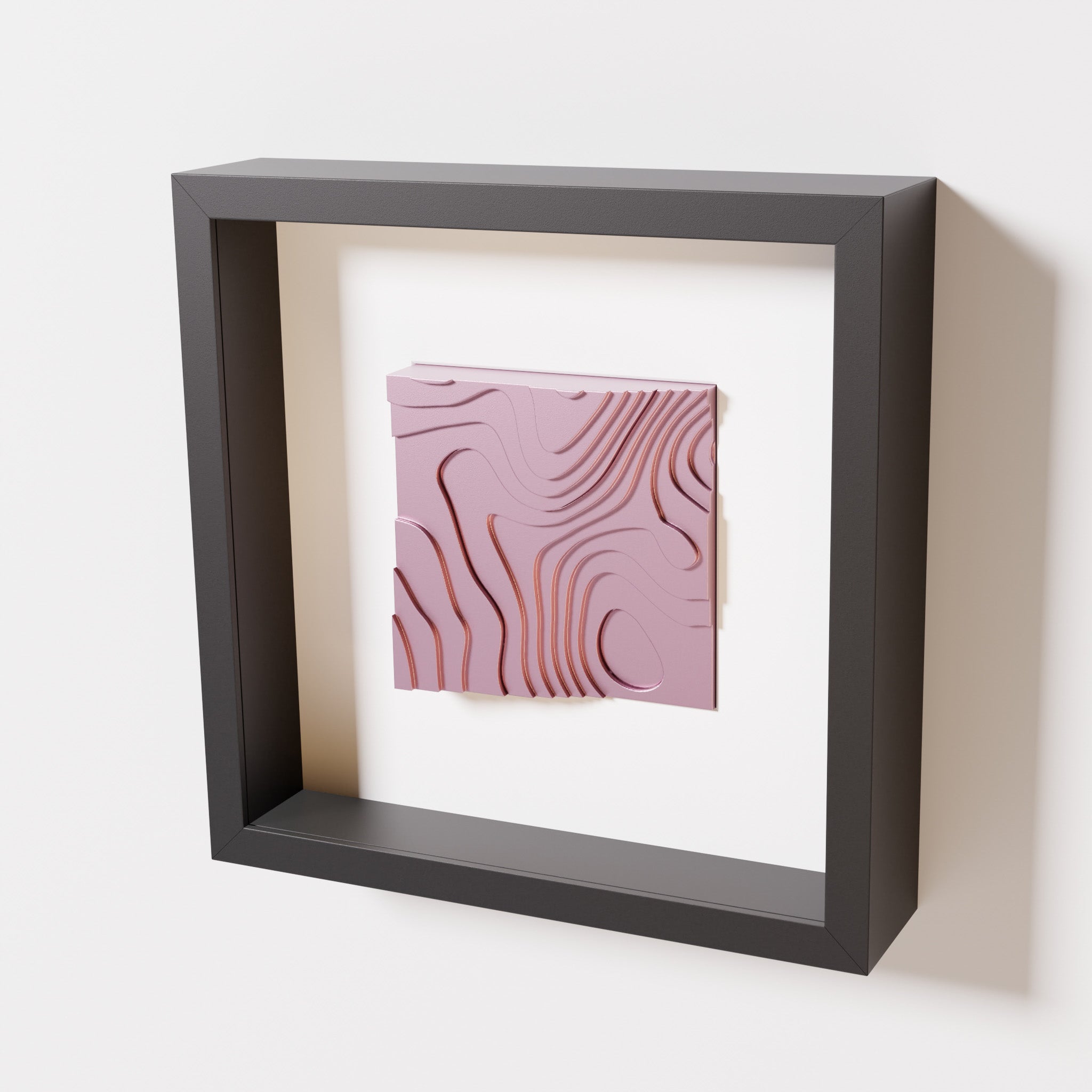 A close-up of a black shadowbox frame containing a metallic rose artwork depicting flowing contour lines inspired by geographic elevation levels, showcasing reflective pink details.