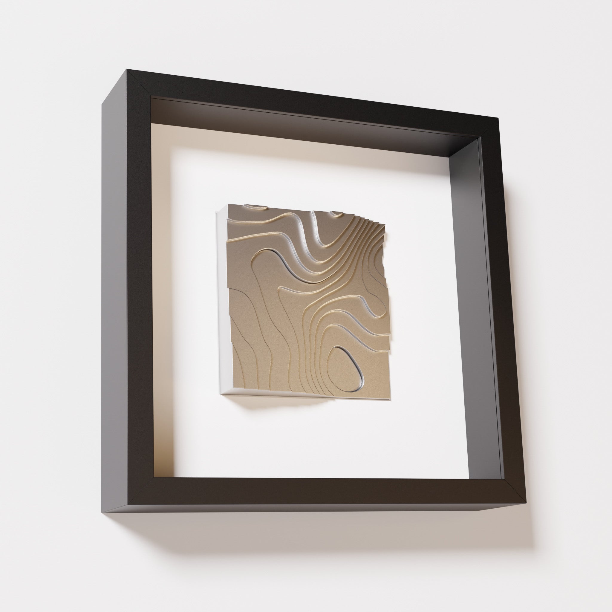 A close-up of a black shadowbox frame containing a chrome silver artwork depicting flowing contour lines inspired by geographic elevation levels, showcasing reflective silver details.