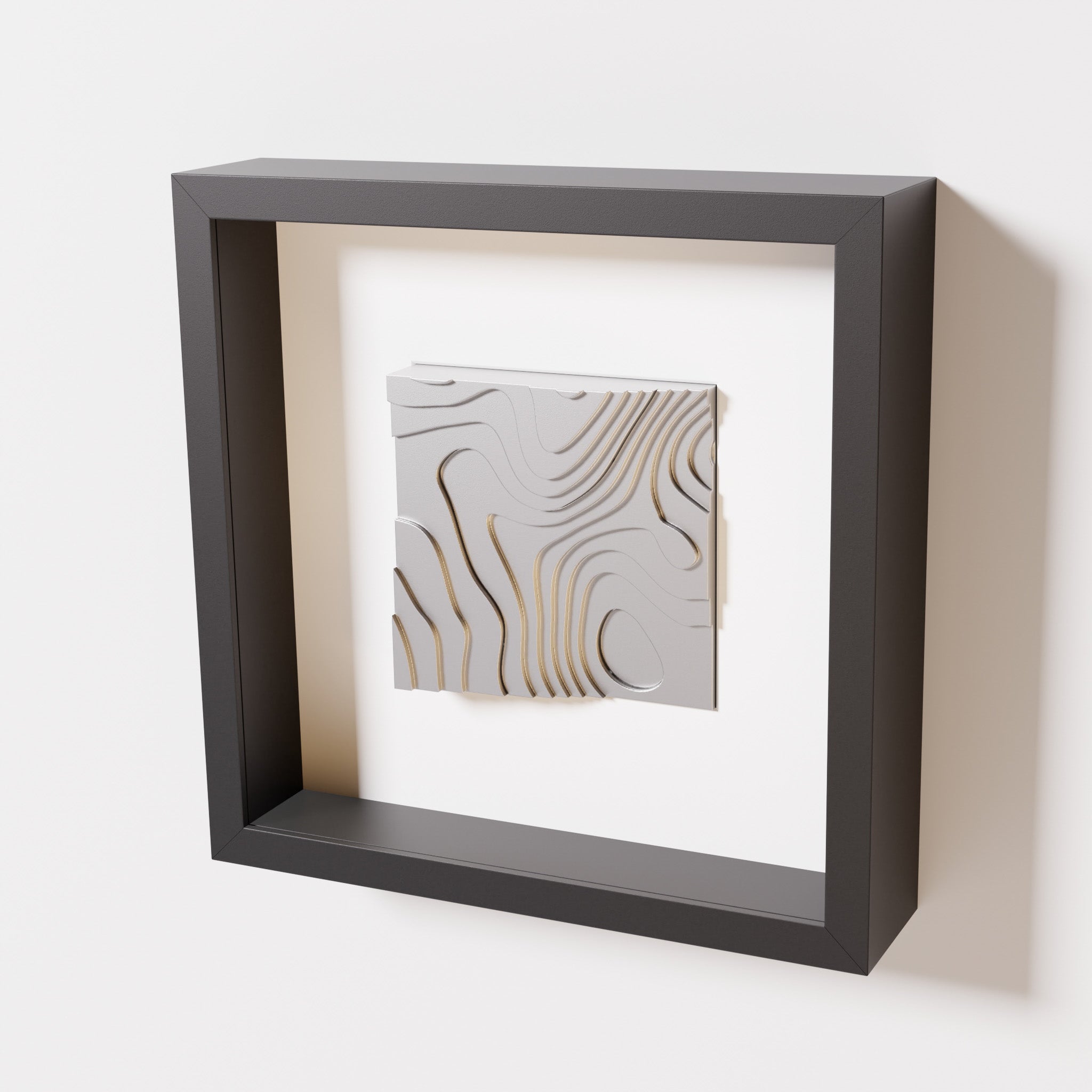 A close-up of a black shadowbox frame containing a chrome silver artwork depicting flowing contour lines inspired by geographic elevation levels, showcasing reflective silver details.