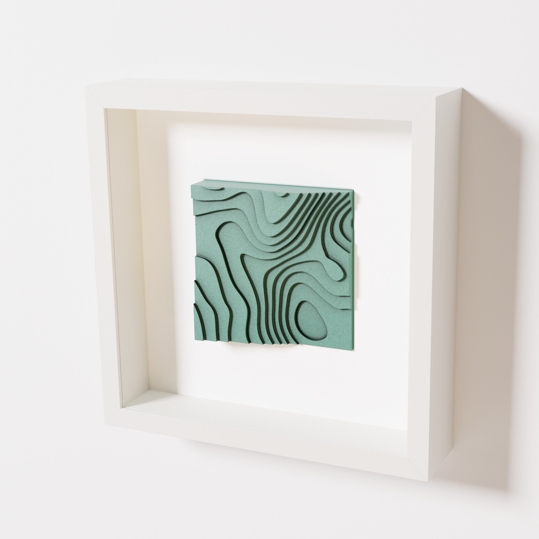 A close-up of a white shadowbox frame containing an old patina artwork depicting flowing contour lines inspired by geographic elevation levels, showcasing intricate geometric details with a textured green finish.