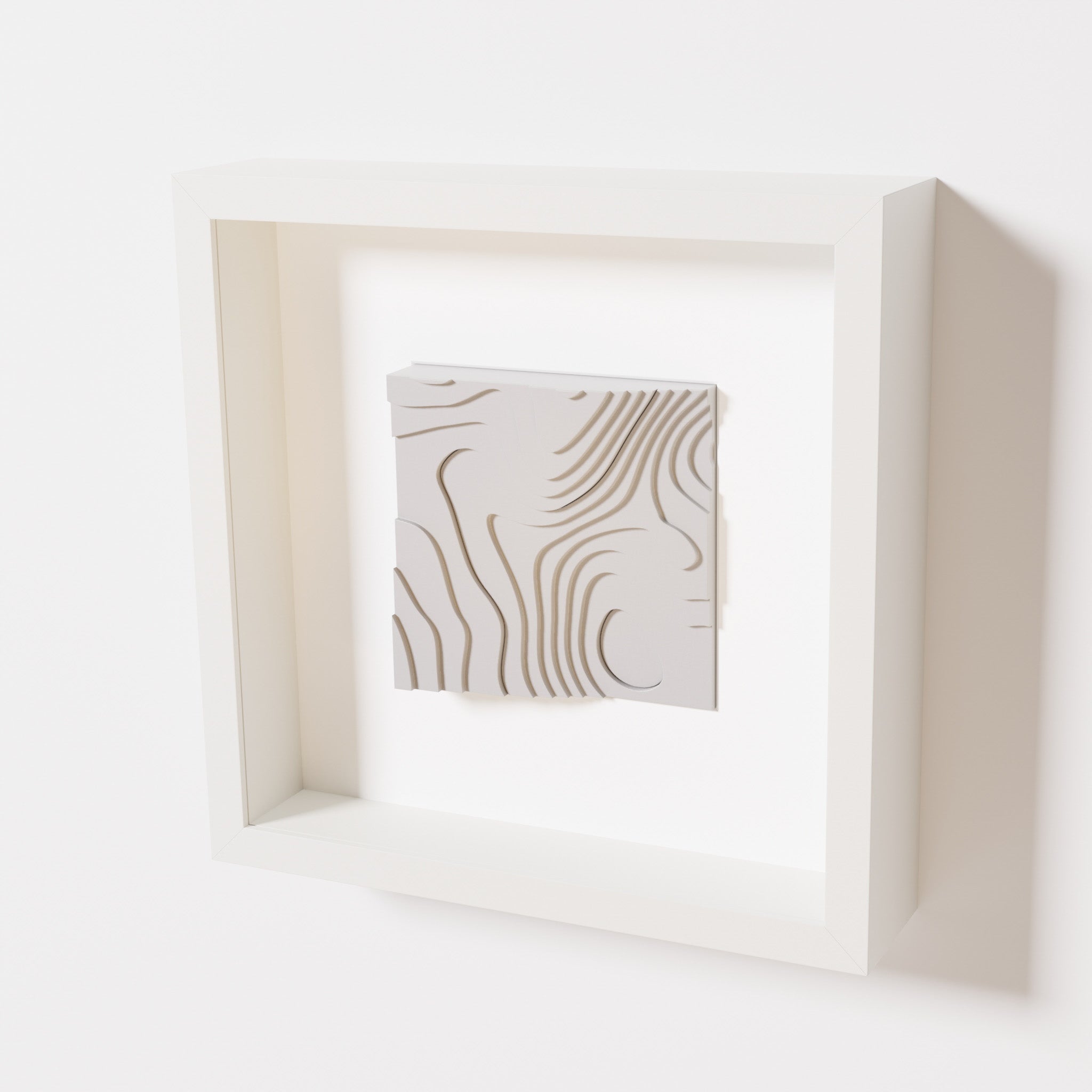 A close-up of a white shadowbox frame containing a marble white artwork depicting flowing contour lines inspired by geographic elevation levels, showcasing intricate geometric details.