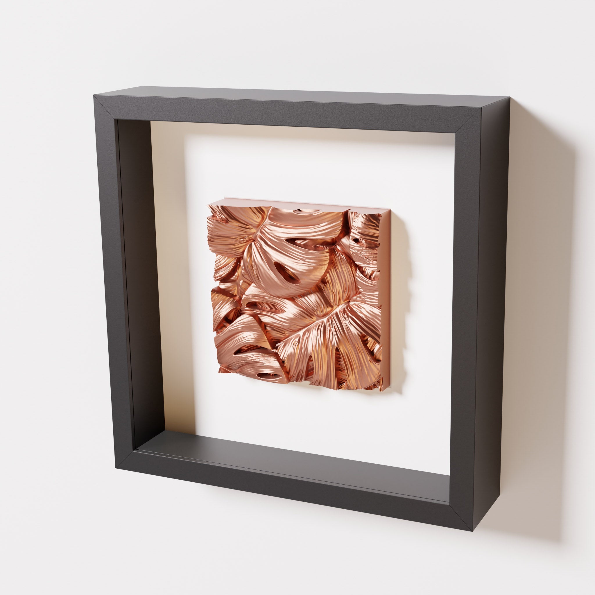 A close-up of a black shadowbox frame containing a chrome copper artwork featuring layered Monstera leaves, showcasing reflective copper highlights and intricate overlapping details.