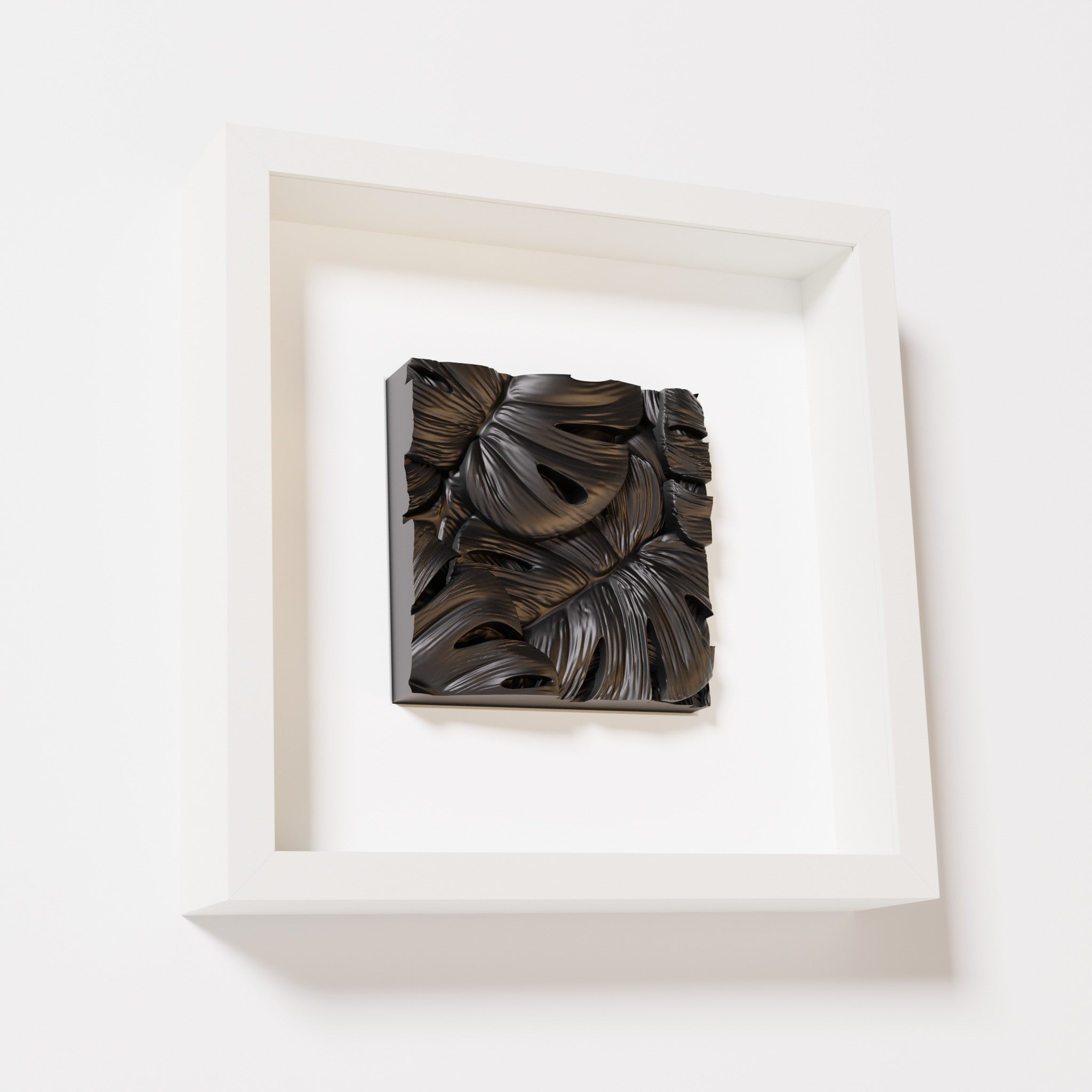 A close-up of a white shadowbox frame containing a matte black artwork featuring layered Monstera leaves, showcasing intricate overlapping details and deep shadows.