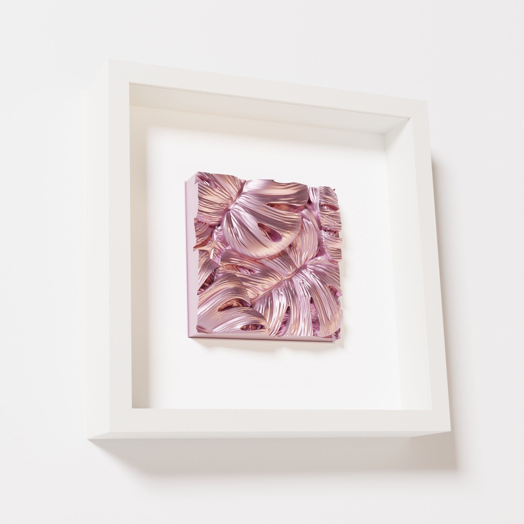 A close-up of a white shadowbox frame containing a metallic rose artwork featuring layered Monstera leaves, showcasing reflective pink highlights and intricate overlapping details.