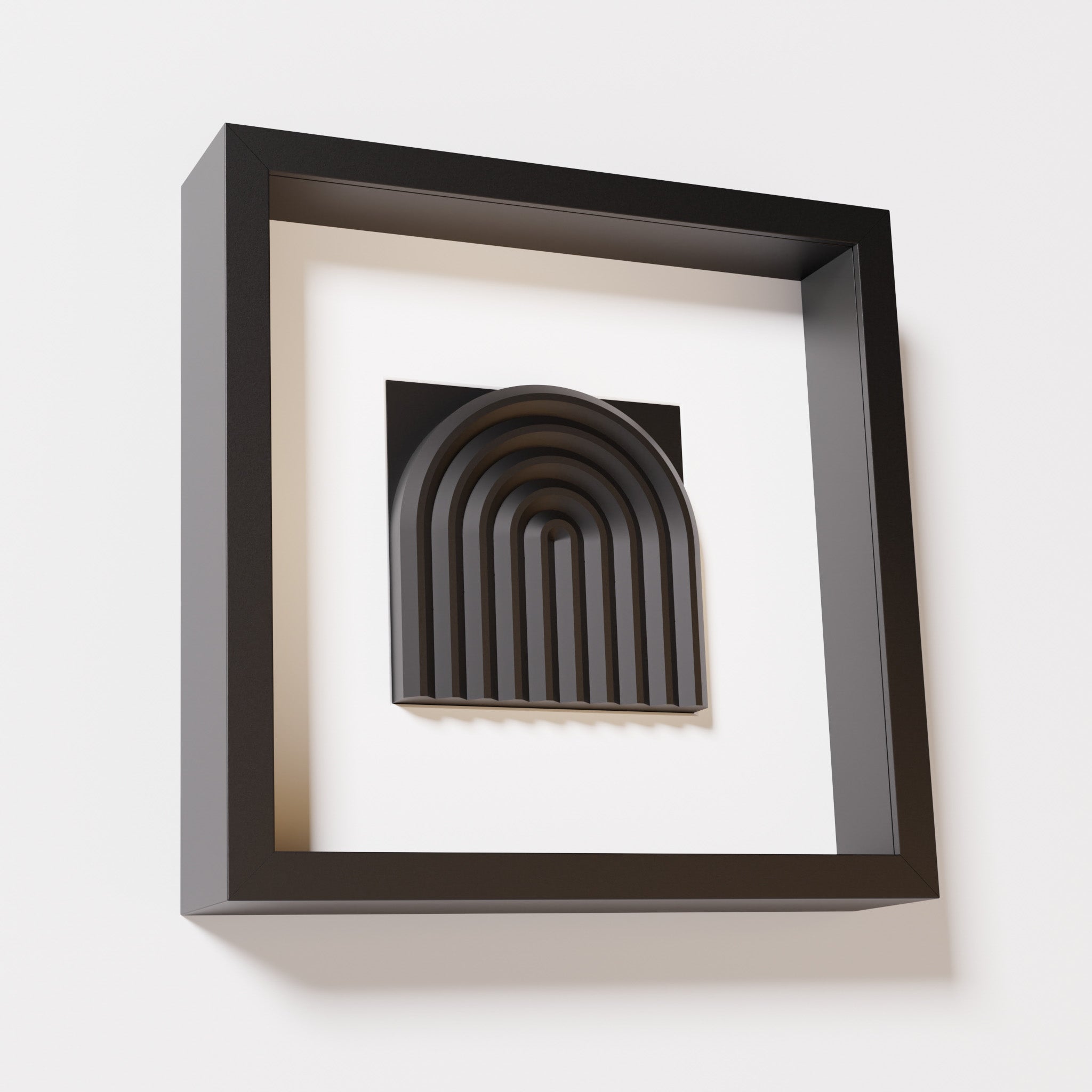 A close-up of a black shadowbox frame containing a matte black artwork featuring the gentle arc of a rainbow design, showcasing its smooth, layered texture and intricate curvature.