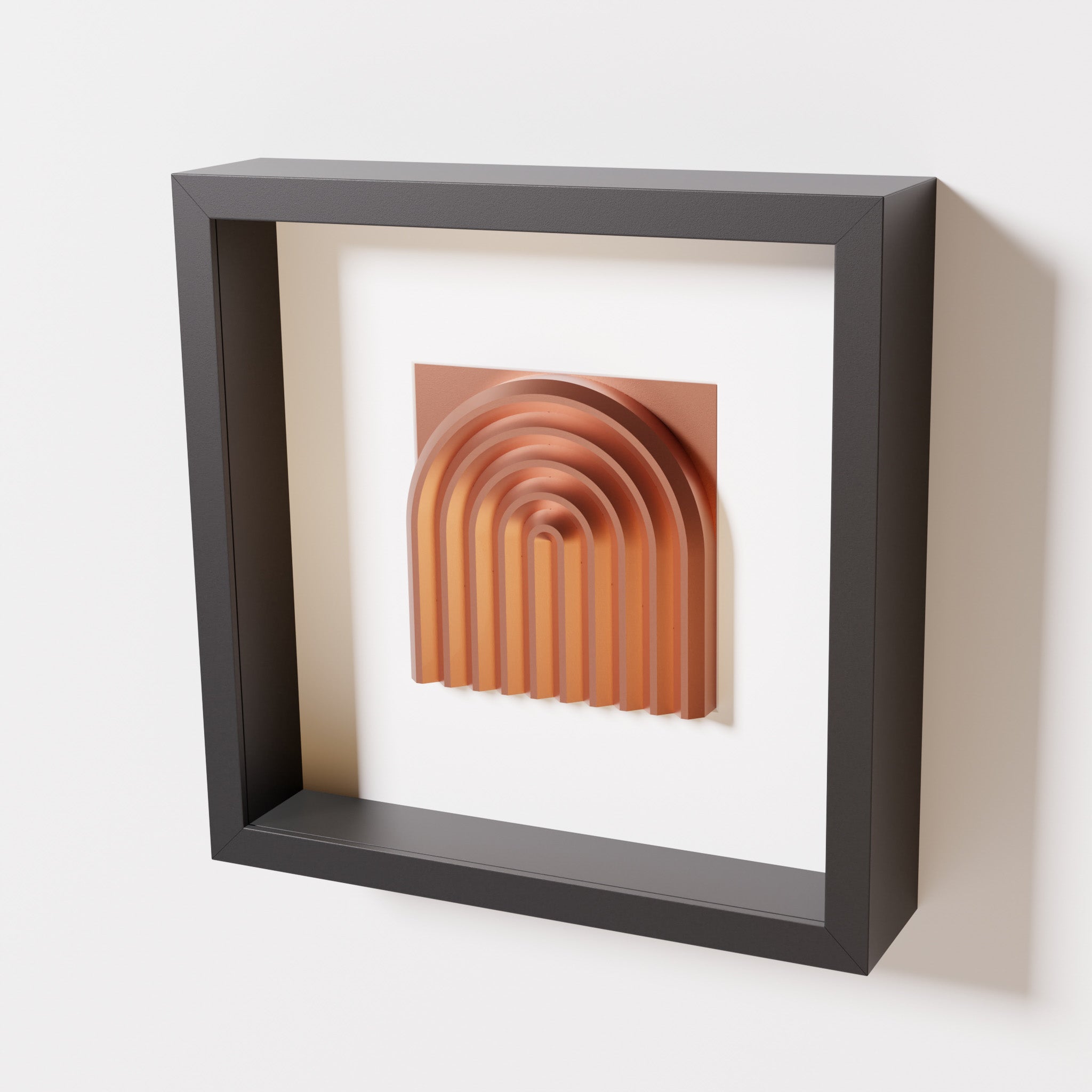 A close-up of a black shadowbox frame containing a chrome copper artwork featuring the gentle arc of a rainbow design, showcasing its shiny copper highlights and layered textures.