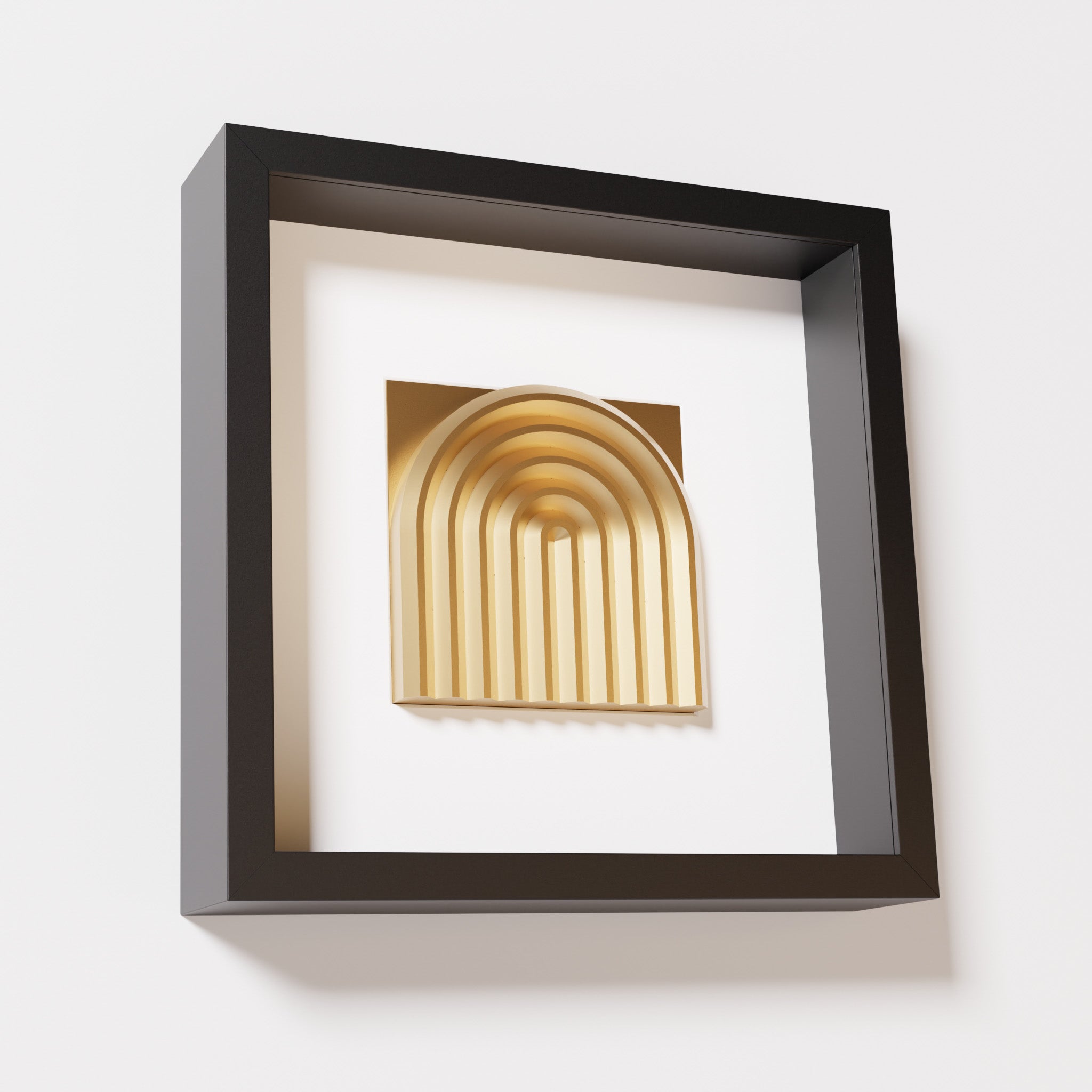 A close-up of a black shadowbox frame containing a chrome gold artwork featuring the gentle arc of a rainbow design, showcasing its reflective golden highlights and detailed curves.