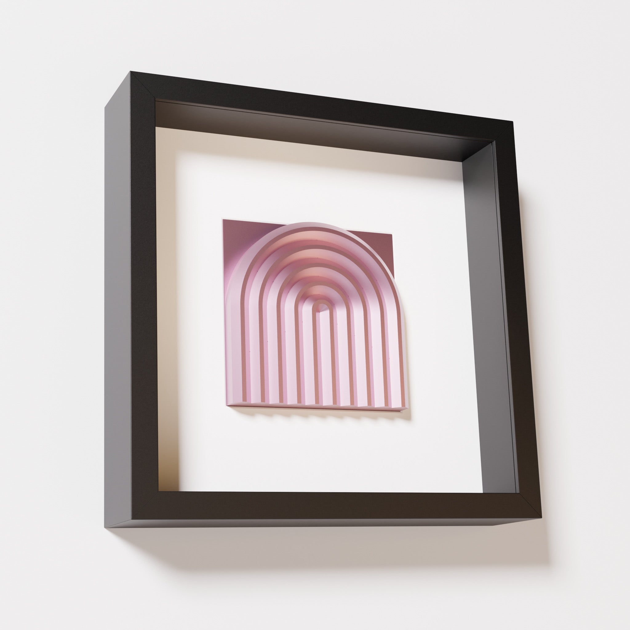 A close-up of a black shadowbox frame containing a metallic rose artwork featuring the gentle arc of a rainbow design, showcasing its soft pink sheen and layered curvature.