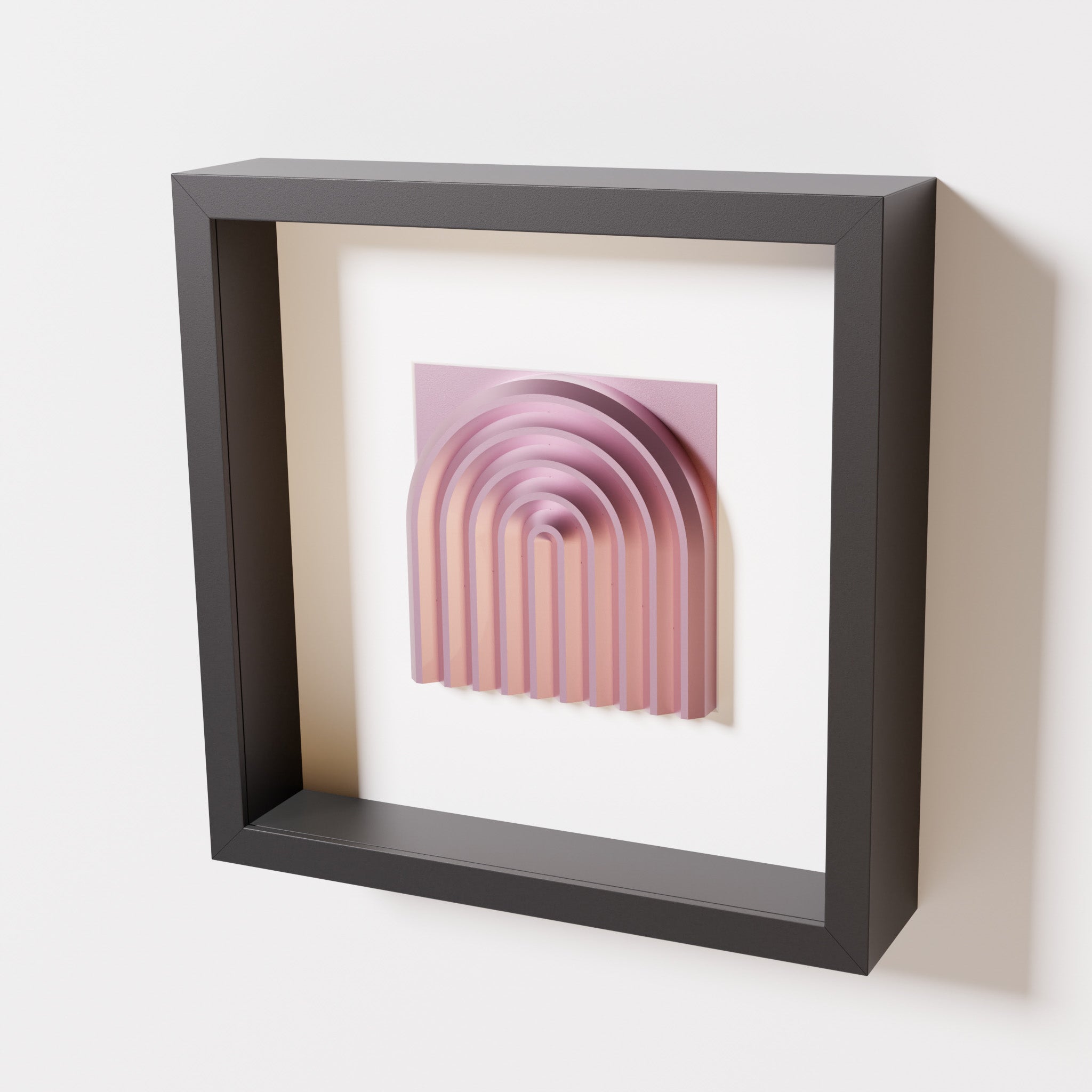 A close-up of a black shadowbox frame containing a metallic rose artwork featuring the gentle arc of a rainbow design, showcasing its soft pink sheen and layered curvature.