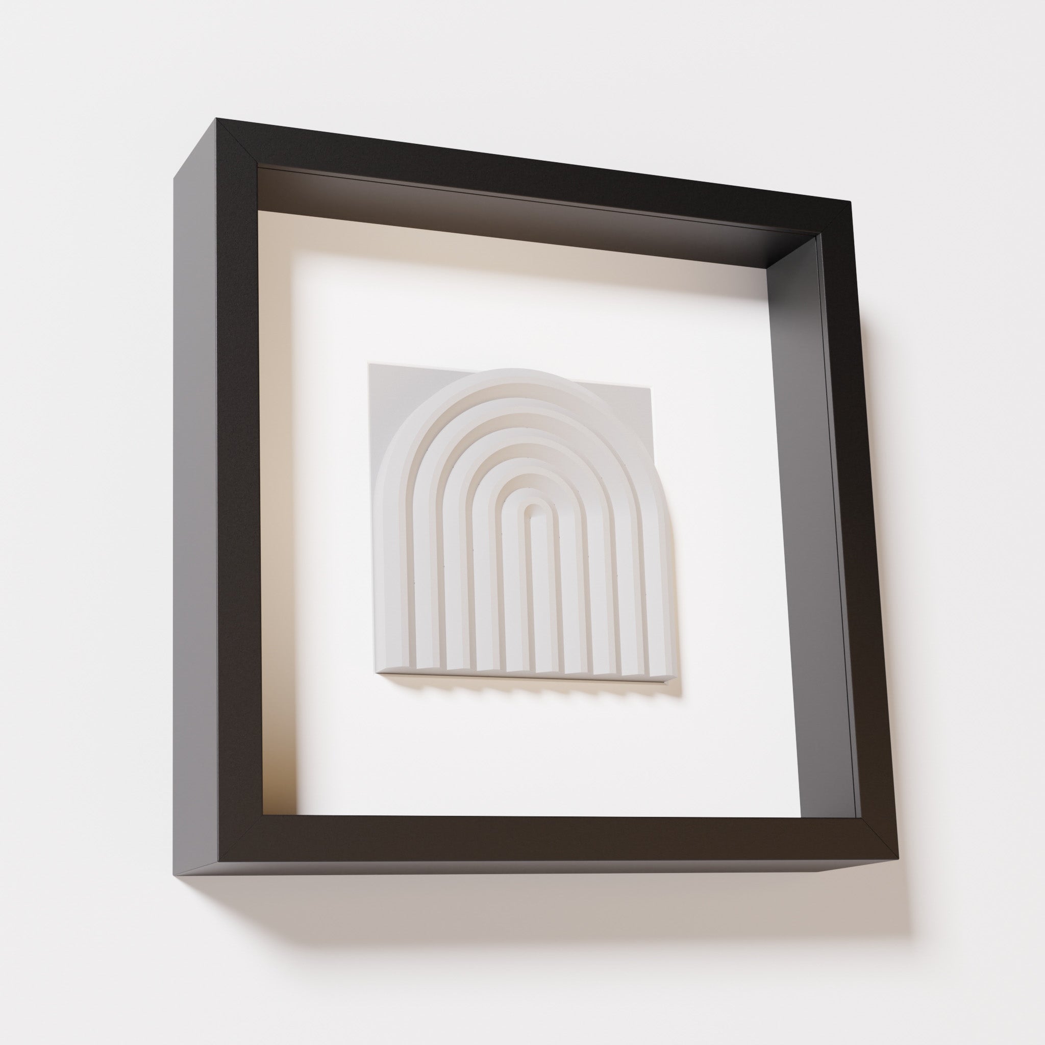 A close-up of a black shadowbox frame containing a marble white artwork featuring the gentle arc of a rainbow design, showcasing its soft texture and detailed curvature.