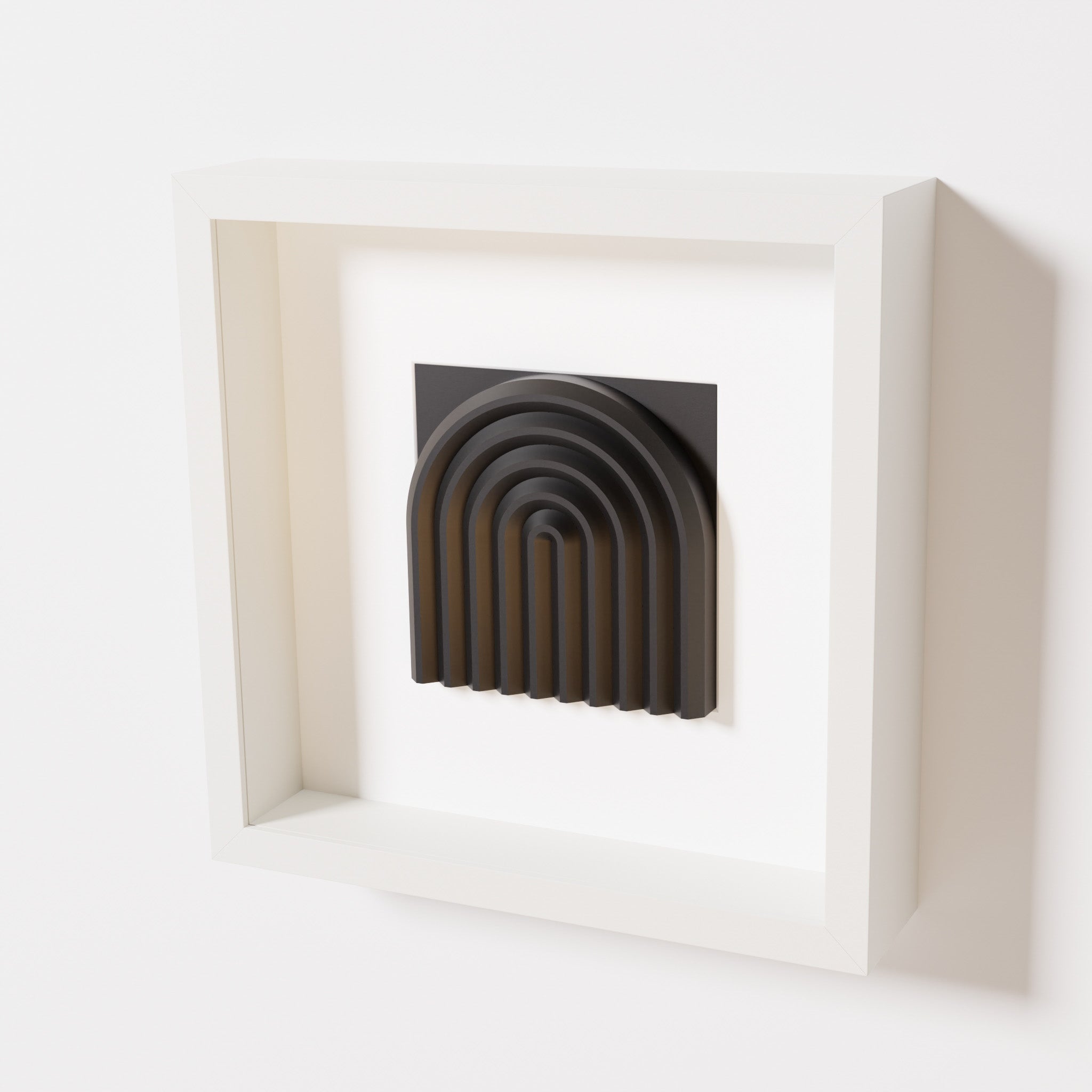 A close-up of a white shadowbox frame containing a matte black artwork featuring the gentle arc of a rainbow design, showcasing its smooth, layered texture and intricate curvature.