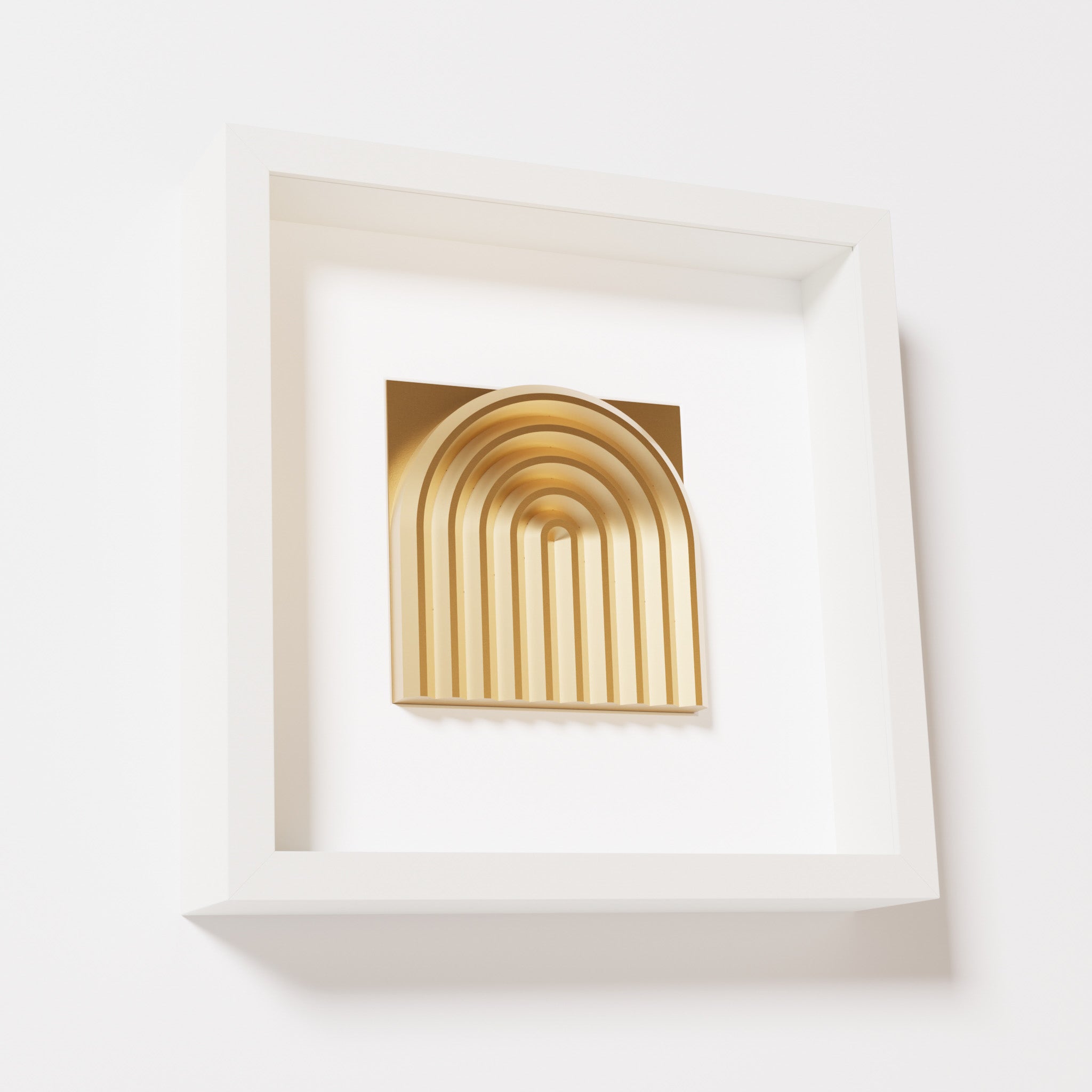 A close-up of a white shadowbox frame containing a chrome gold artwork featuring the gentle arc of a rainbow design, showcasing its reflective golden highlights and detailed curves.