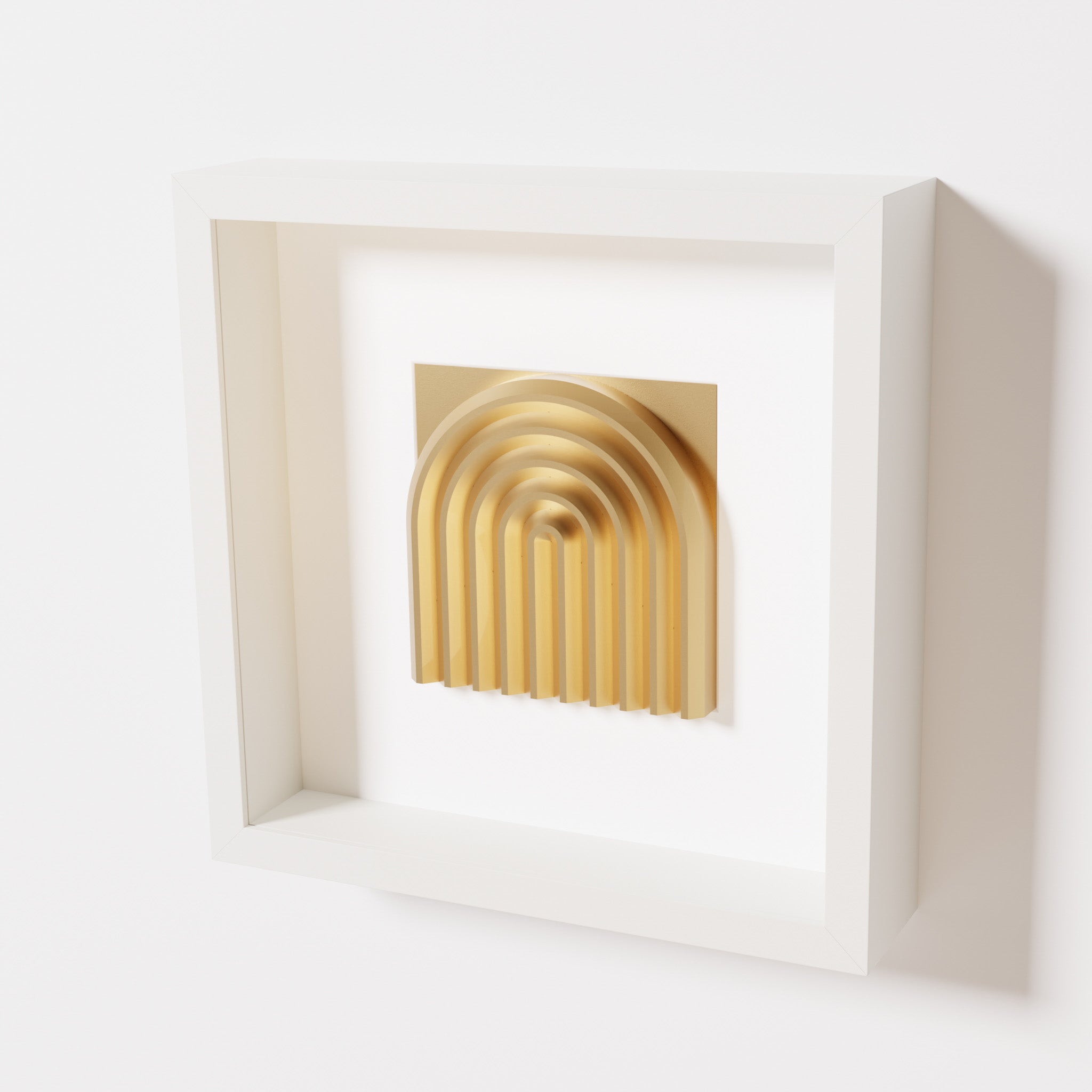 A close-up of a white shadowbox frame containing a chrome gold artwork featuring the gentle arc of a rainbow design, showcasing its reflective golden highlights and detailed curves.