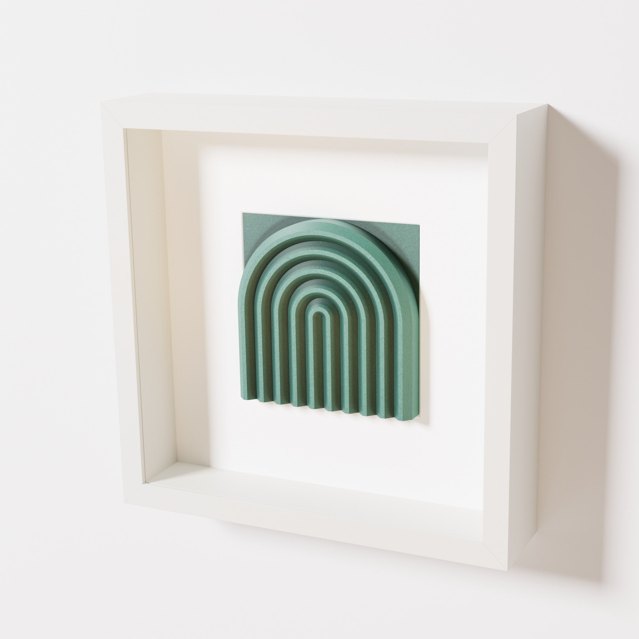 A close-up of a white shadowbox frame containing an old patina artwork featuring the gentle arc of a rainbow design, showcasing its textured green finish and detailed layering.