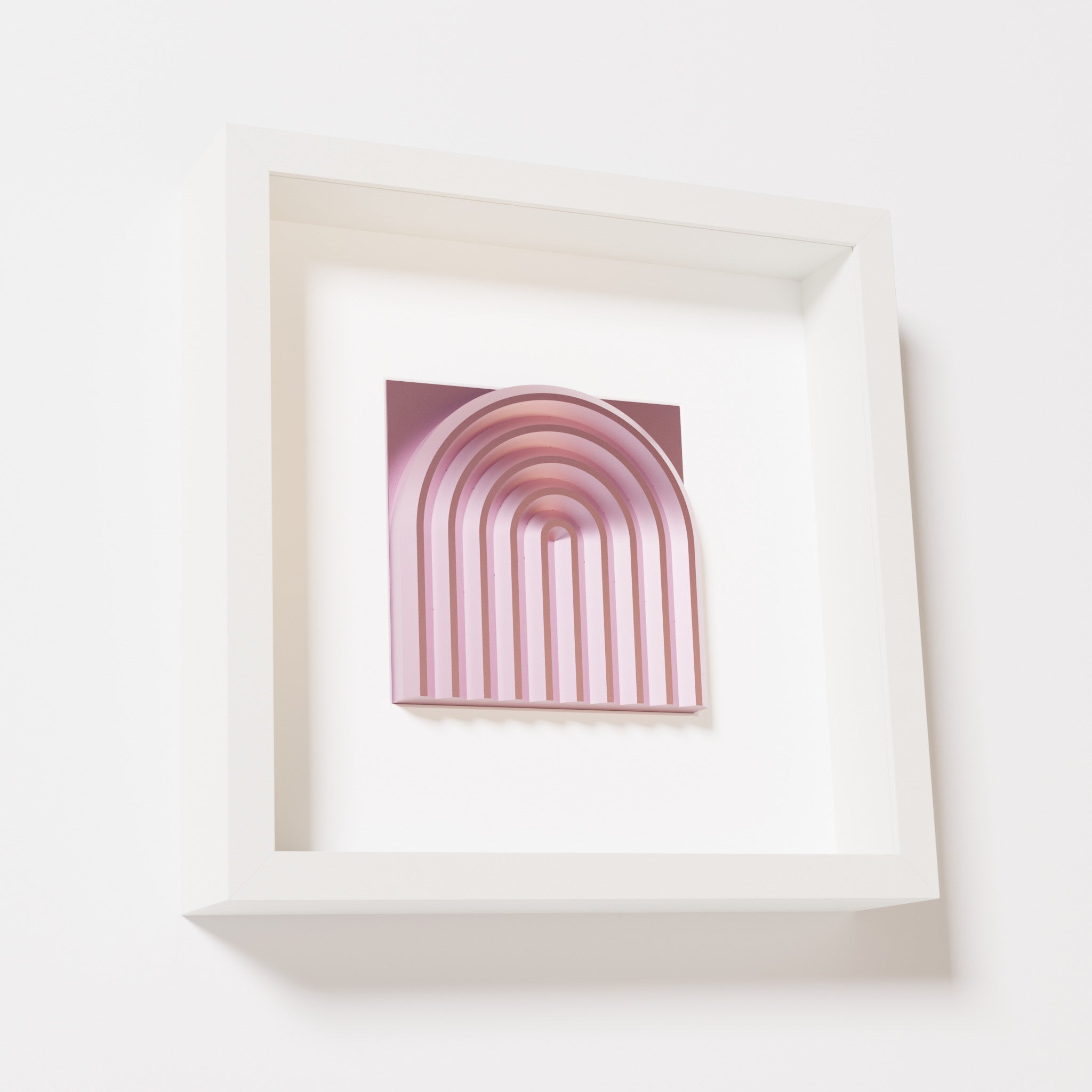 A close-up of a white shadowbox frame containing a metallic rose artwork featuring the gentle arc of a rainbow design, showcasing its soft pink sheen and layered curvature.