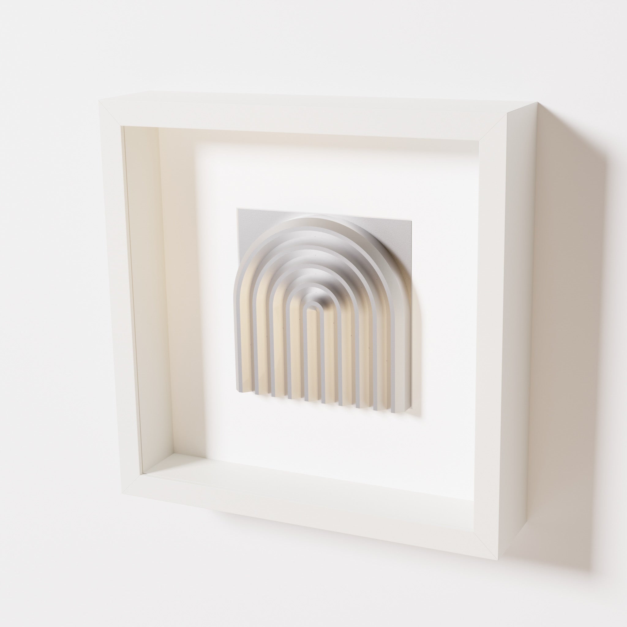 A close-up of a white shadowbox frame containing a chrome silver artwork featuring the gentle arc of a rainbow design, showcasing its reflective silver highlights and elegant curves.