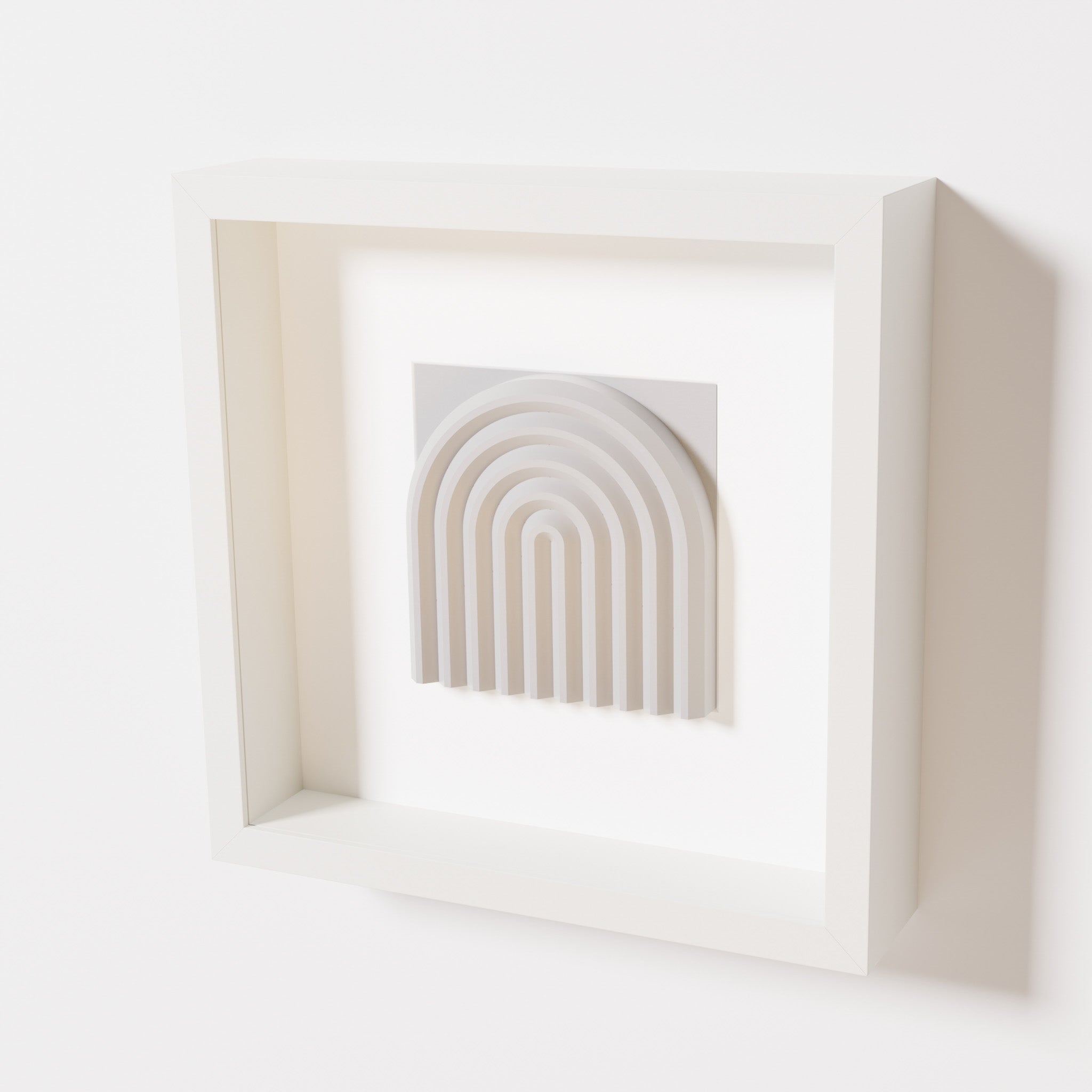 A close-up of a white shadowbox frame containing a marble white artwork featuring the gentle arc of a rainbow design, showcasing its soft texture and detailed curvature.