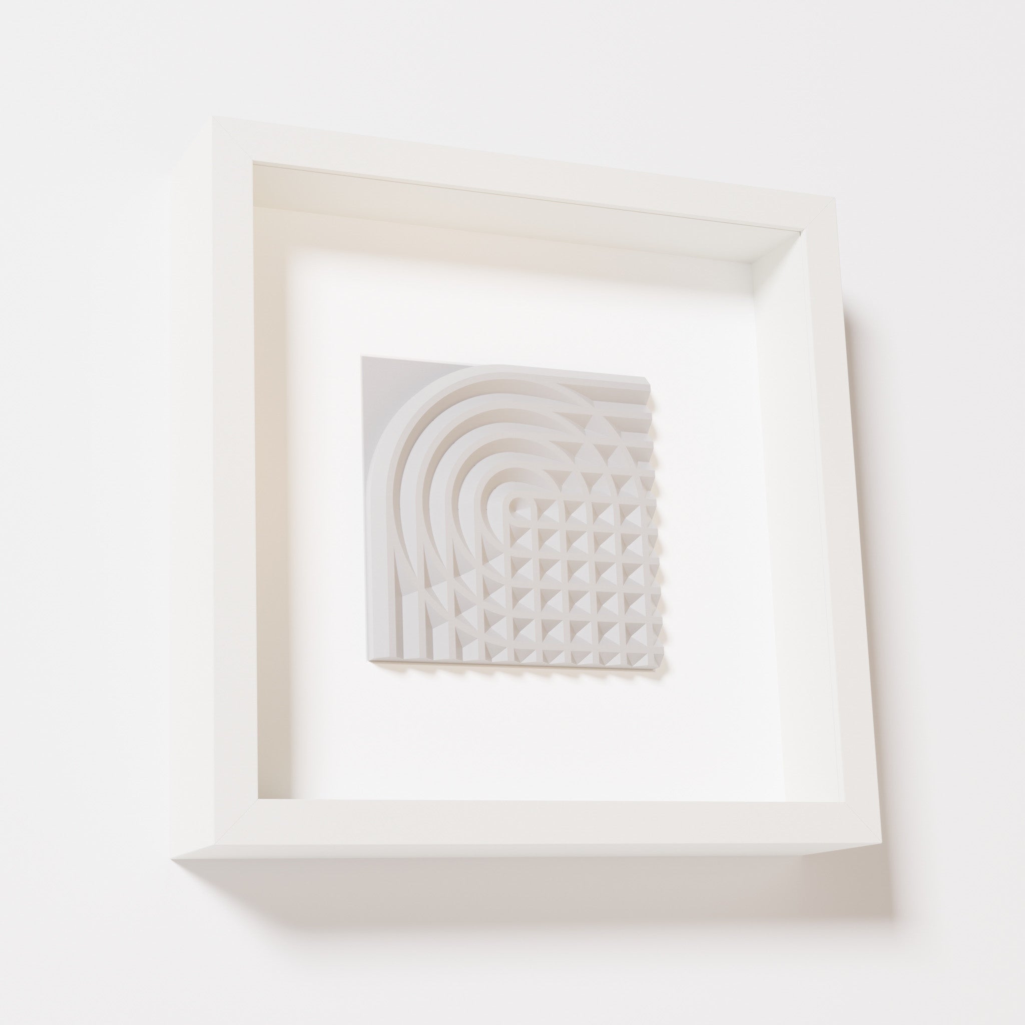 A close-up of a white shadowbox frame containing a marble white artwork featuring the elegant arcs and geometric grid of 'Rainbow II,' showcasing a smooth and refined texture.