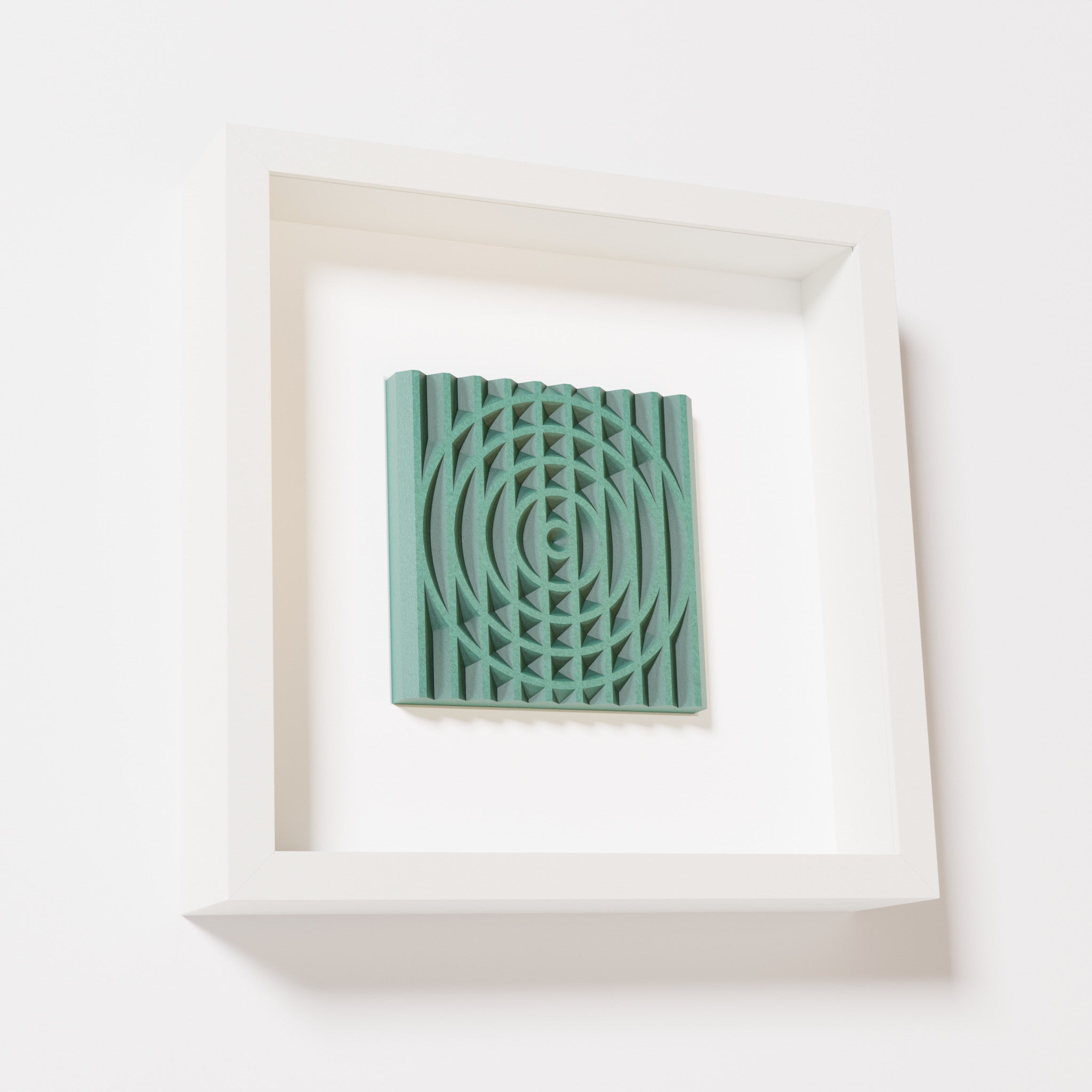 A close-up of a white shadowbox frame containing an old patina artwork featuring the elegant arcs and geometric grid of 'Rainbow III,' showcasing a textured green finish and intricate detail.