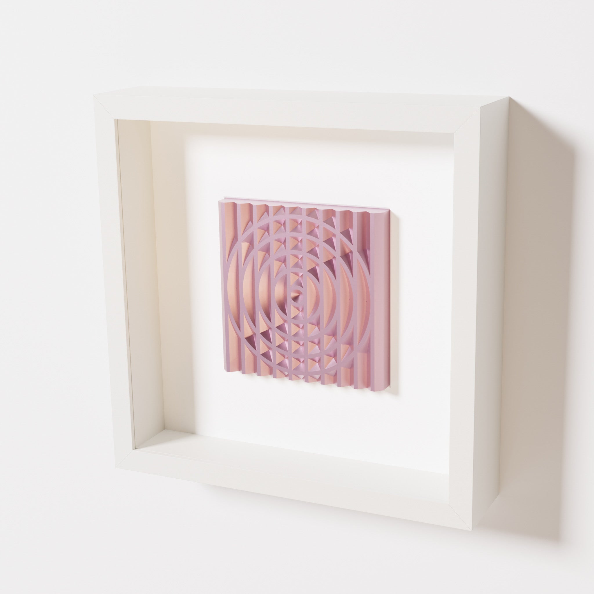 A close-up of a white shadowbox frame containing a metallic rose artwork featuring the elegant arcs and geometric grid of 'Rainbow III,' showcasing reflective pink highlights.