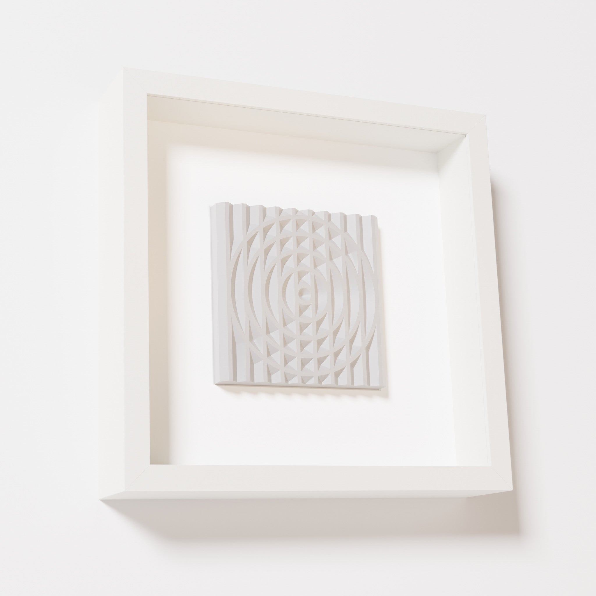 A close-up of a white shadowbox frame containing a marble white artwork featuring the elegant arcs and geometric grid of 'Rainbow III,' emphasizing its smooth texture and refined design.